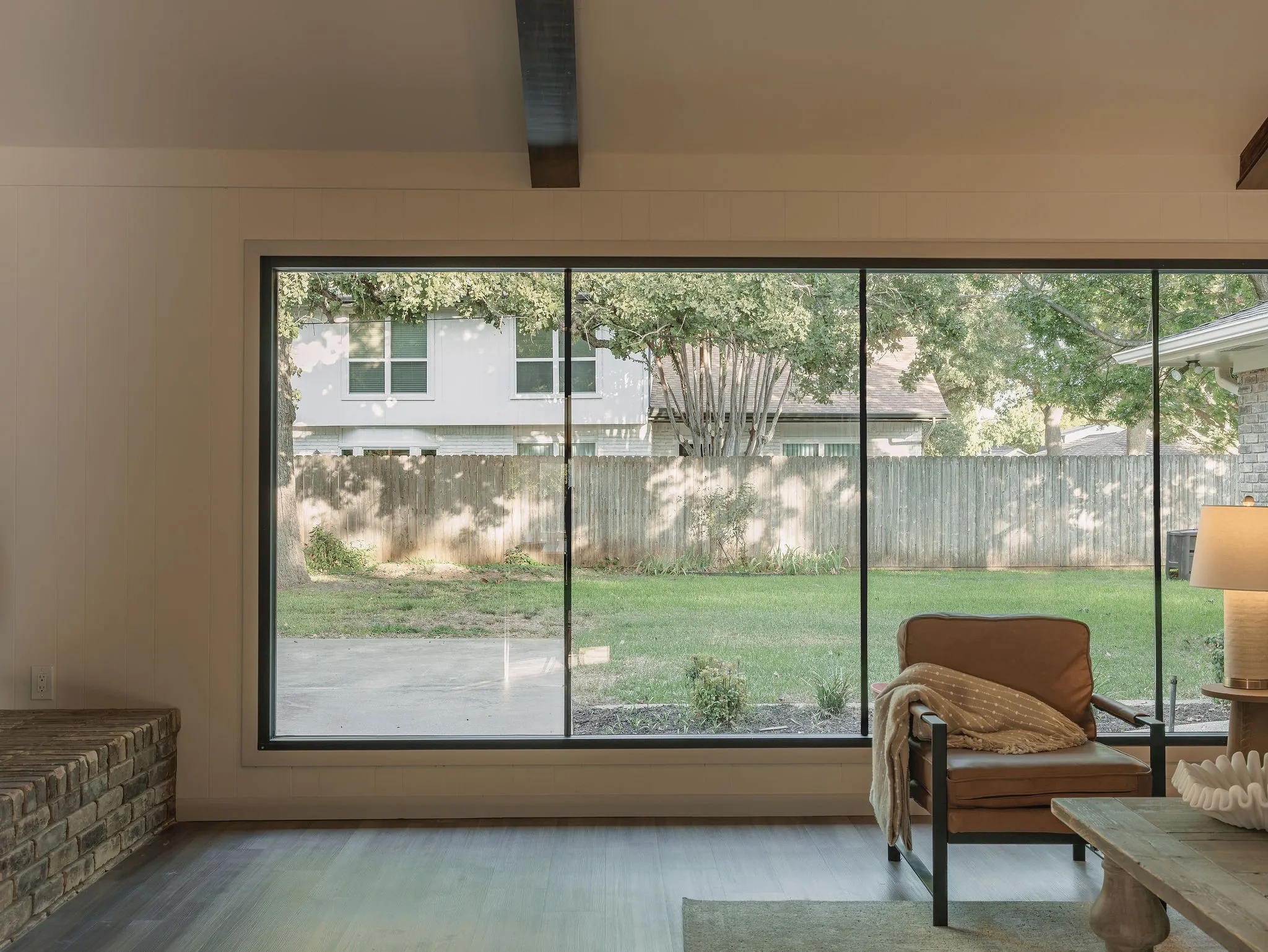 Dramatic storefront grade windows span the living room, bringing in abundant natural light and framing views of the backyard.