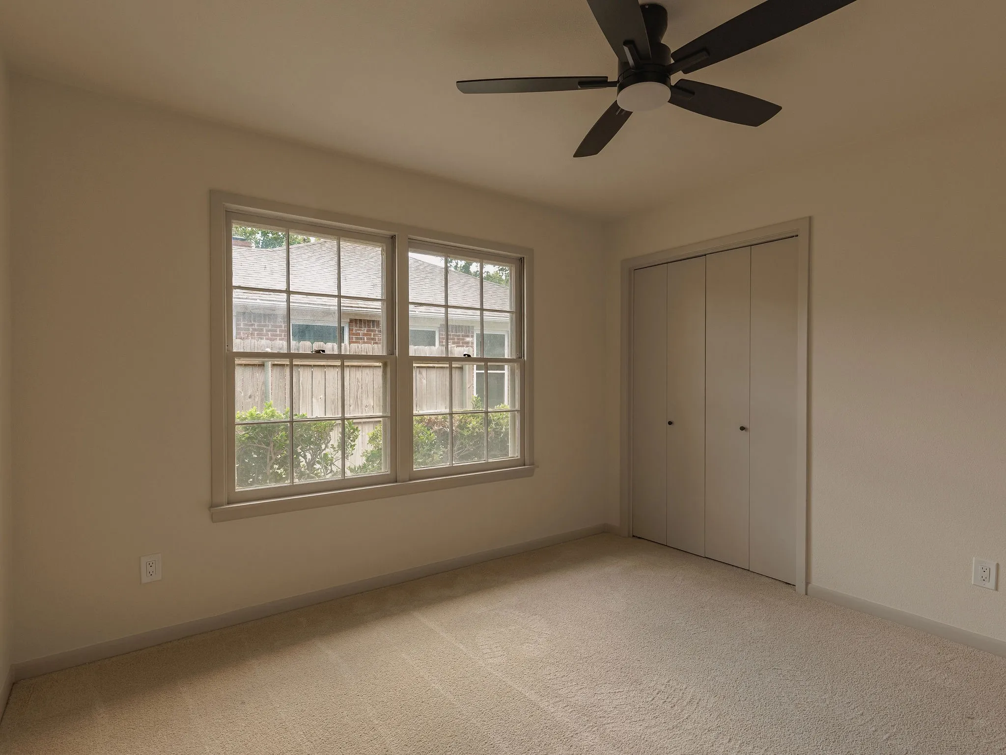 A light filled secondary bedroom with generous closet space and a clean, neutral palette.