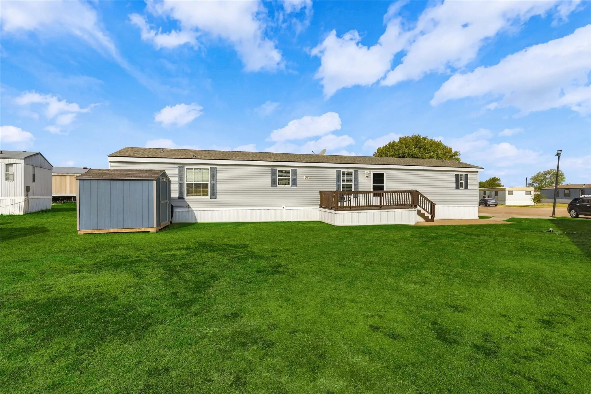 Expansive lawn area with a detached storage shed, a raised deck, and exterior siding