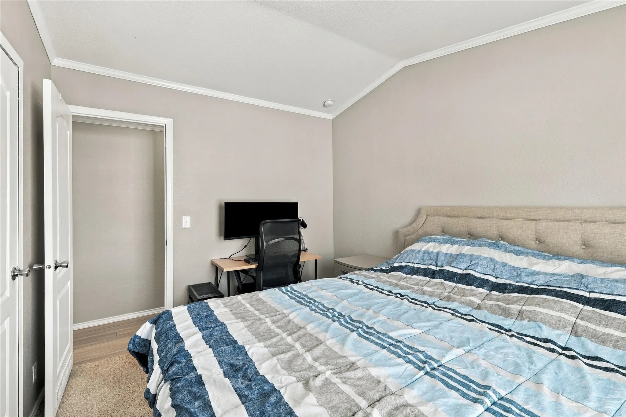 Vaulted ceiling with crown molding, neutral wall color, and light-colored carpeting