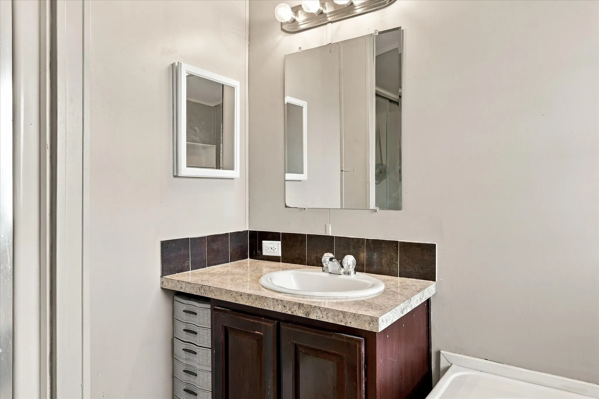 Vanity with integrated sink, patterned countertop, and brown tile backsplash