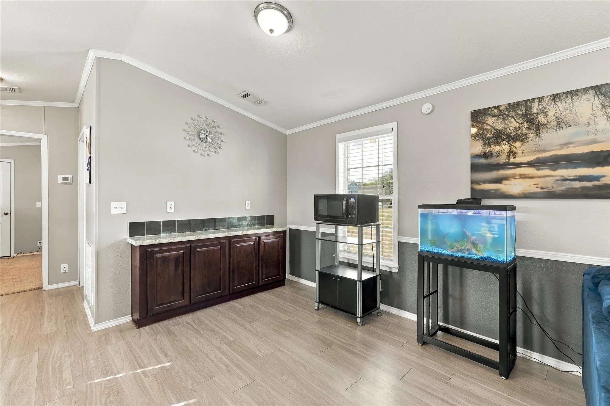 Wood-finish flooring, built-in cabinetry with a stone-finish countertop, and a window with blinds