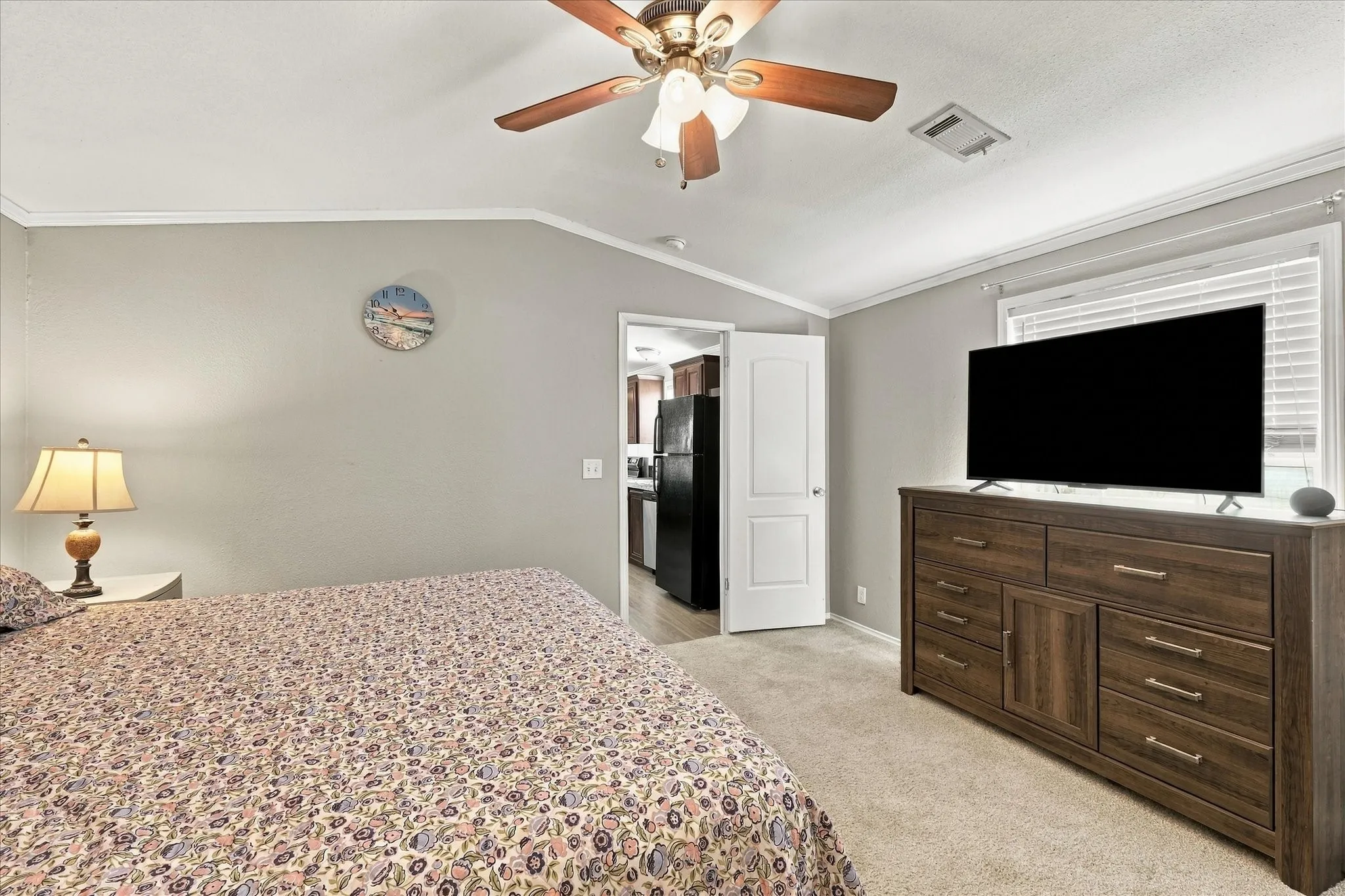 Carpeted room with a ceiling fan, crown molding, and a window with blinds