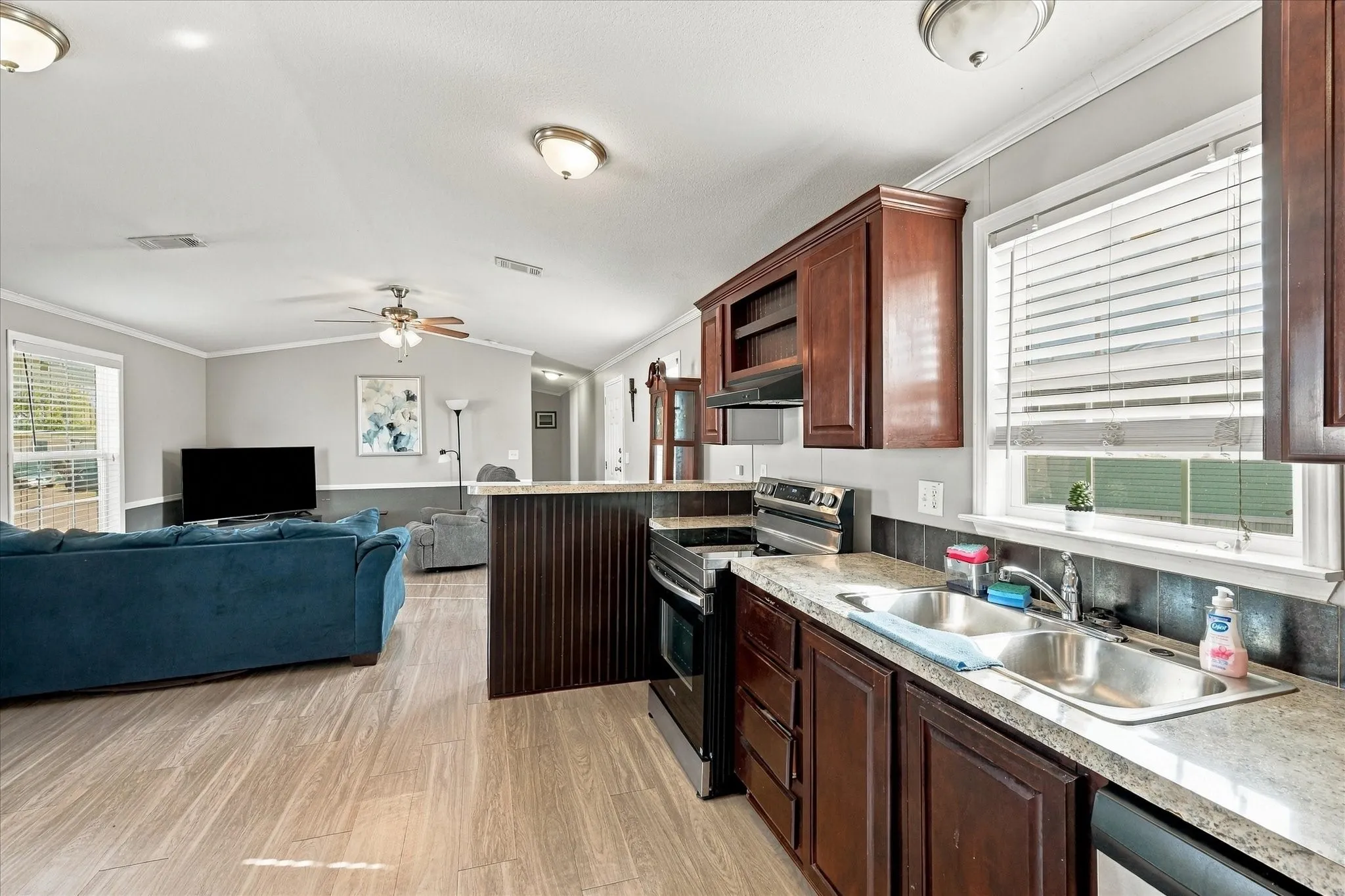 Kitchen featuring wood-finish cabinetry, stainless steel appliances, dual basin sink, and laminate countertops