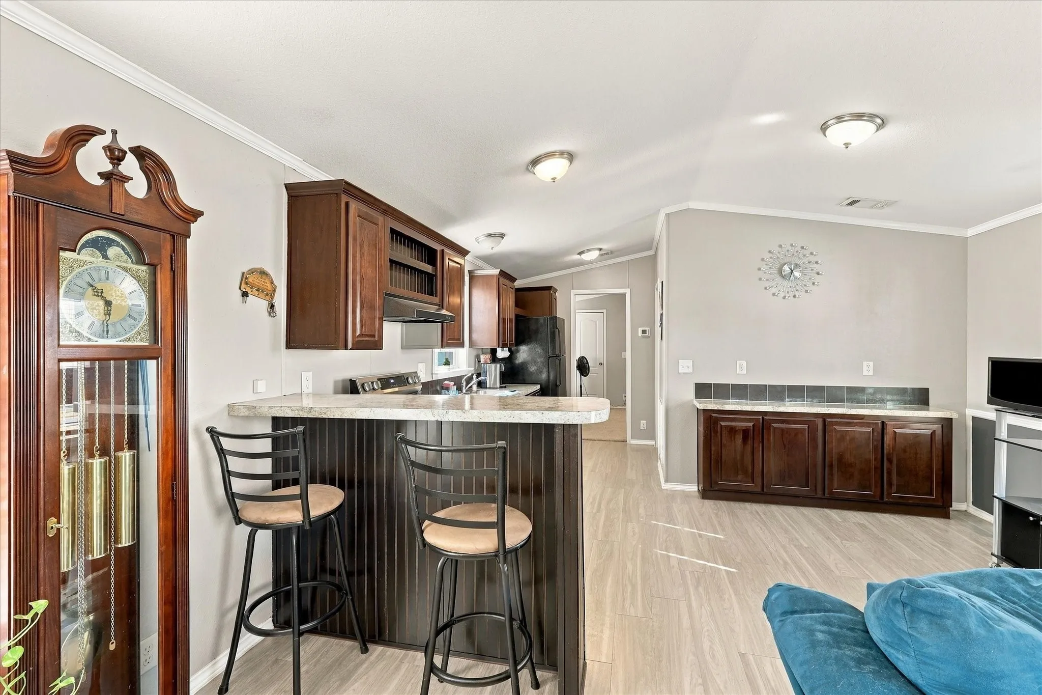 Kitchen island with a breakfast bar, wood-finish cabinetry, light-toned countertops, and tile-look flooring