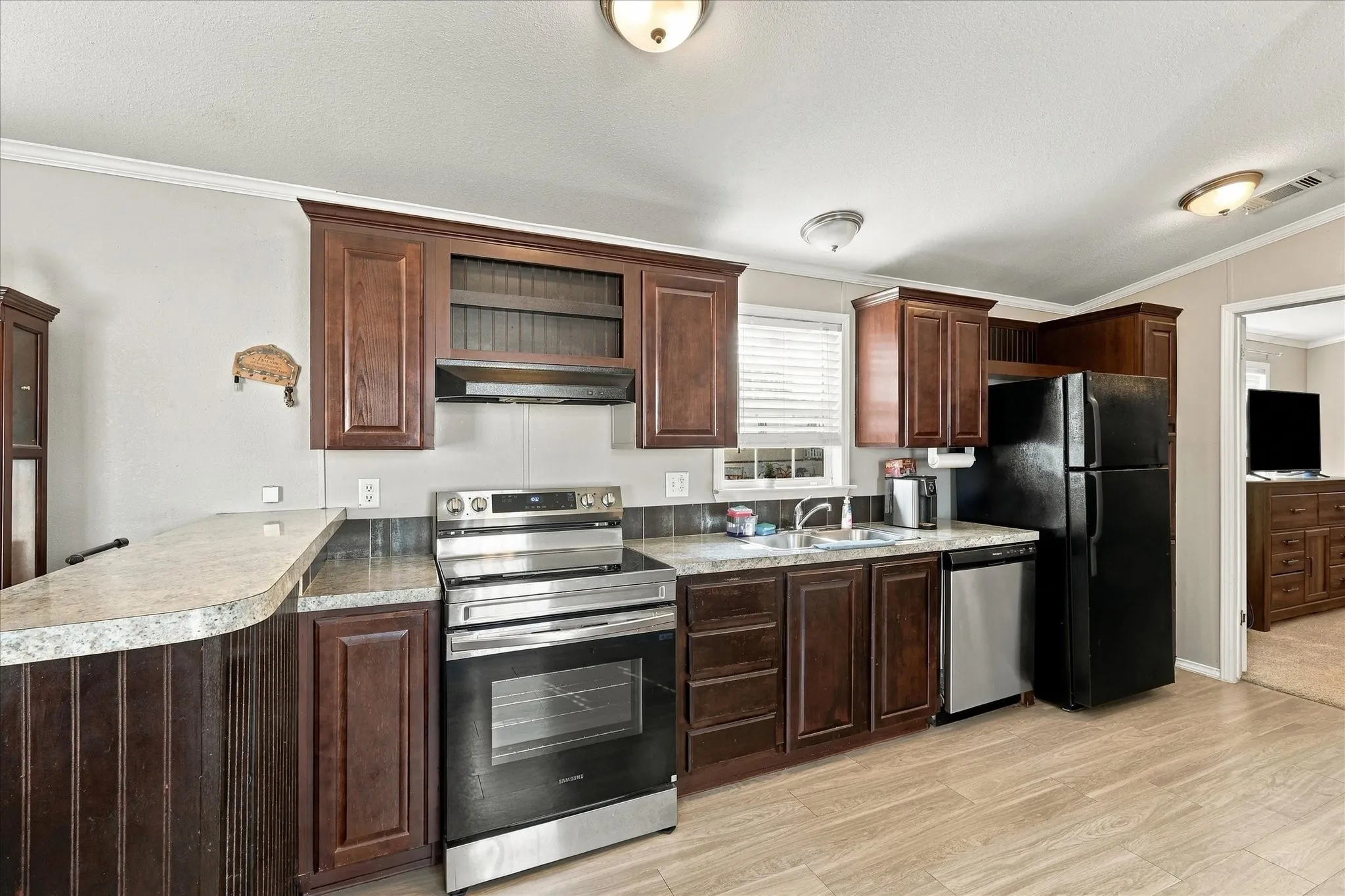 Kitchen featuring wood-finish flooring, dark wood cabinetry, and stainless steel appliances