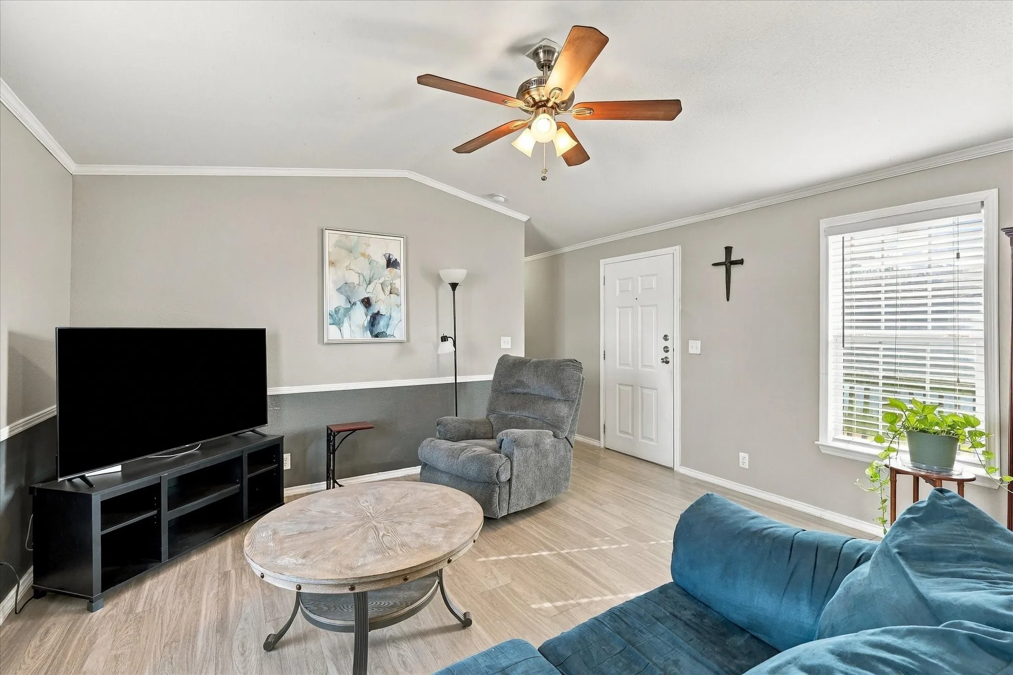 Vaulted ceiling with a ceiling fan, recessed window with blinds, panel interior door, and wood-finish flooring