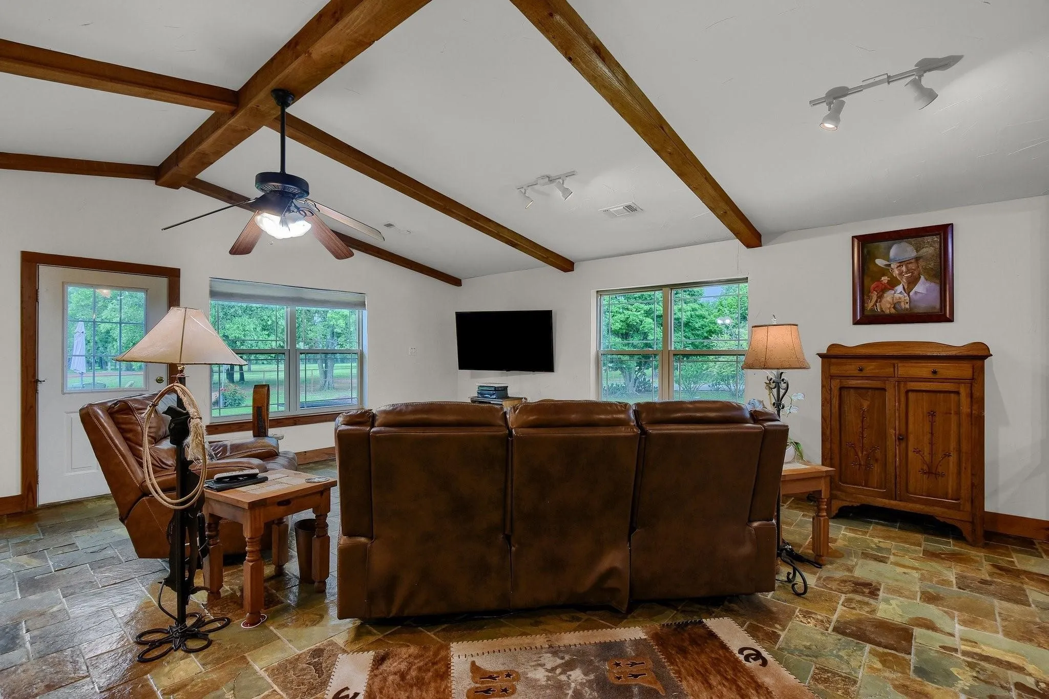 Living room with stone tile floors and a ceiling fan