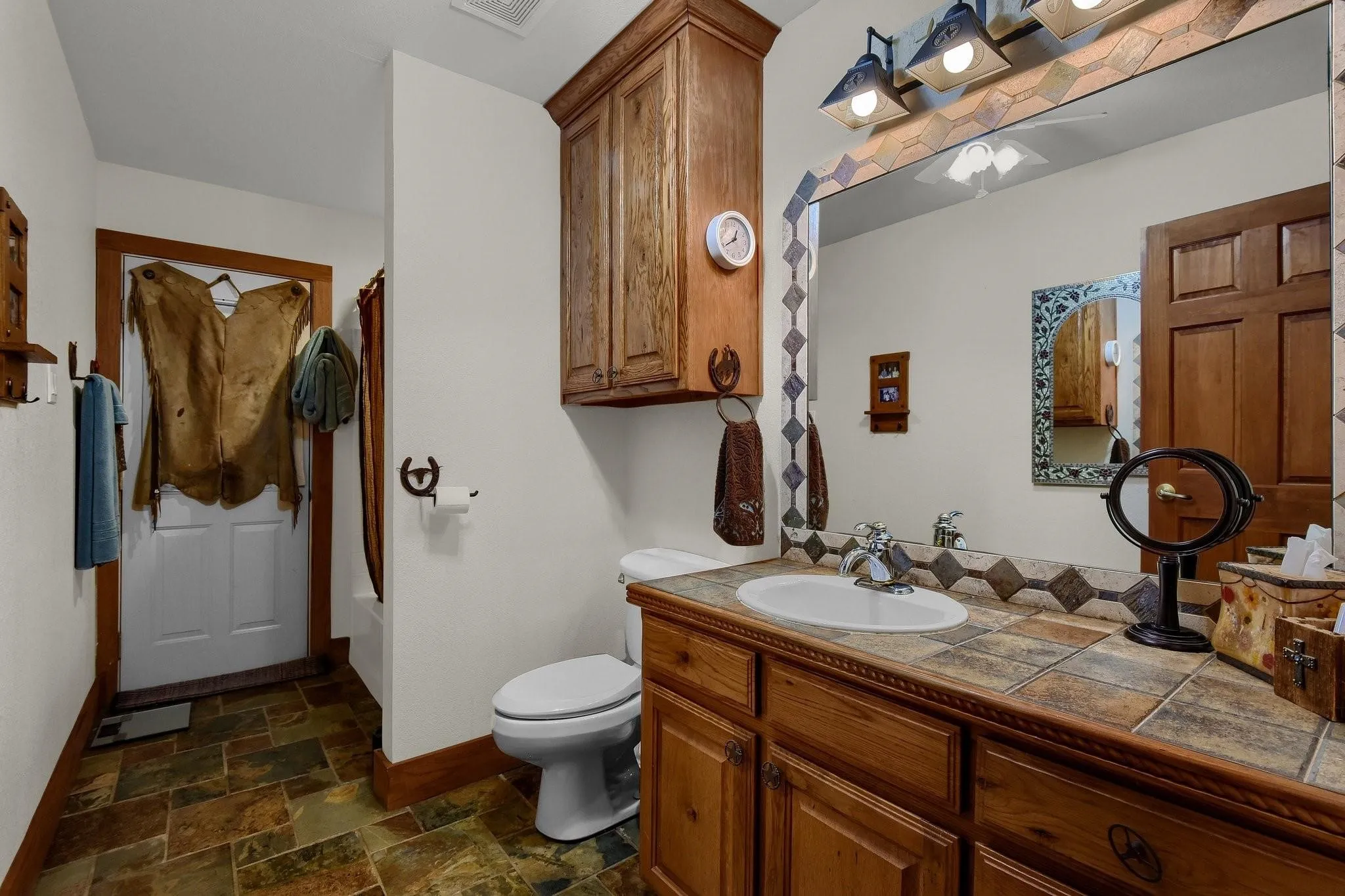 Bathroom featuring stone finish flooring, vanity, and shower / bathtub combination with curtain