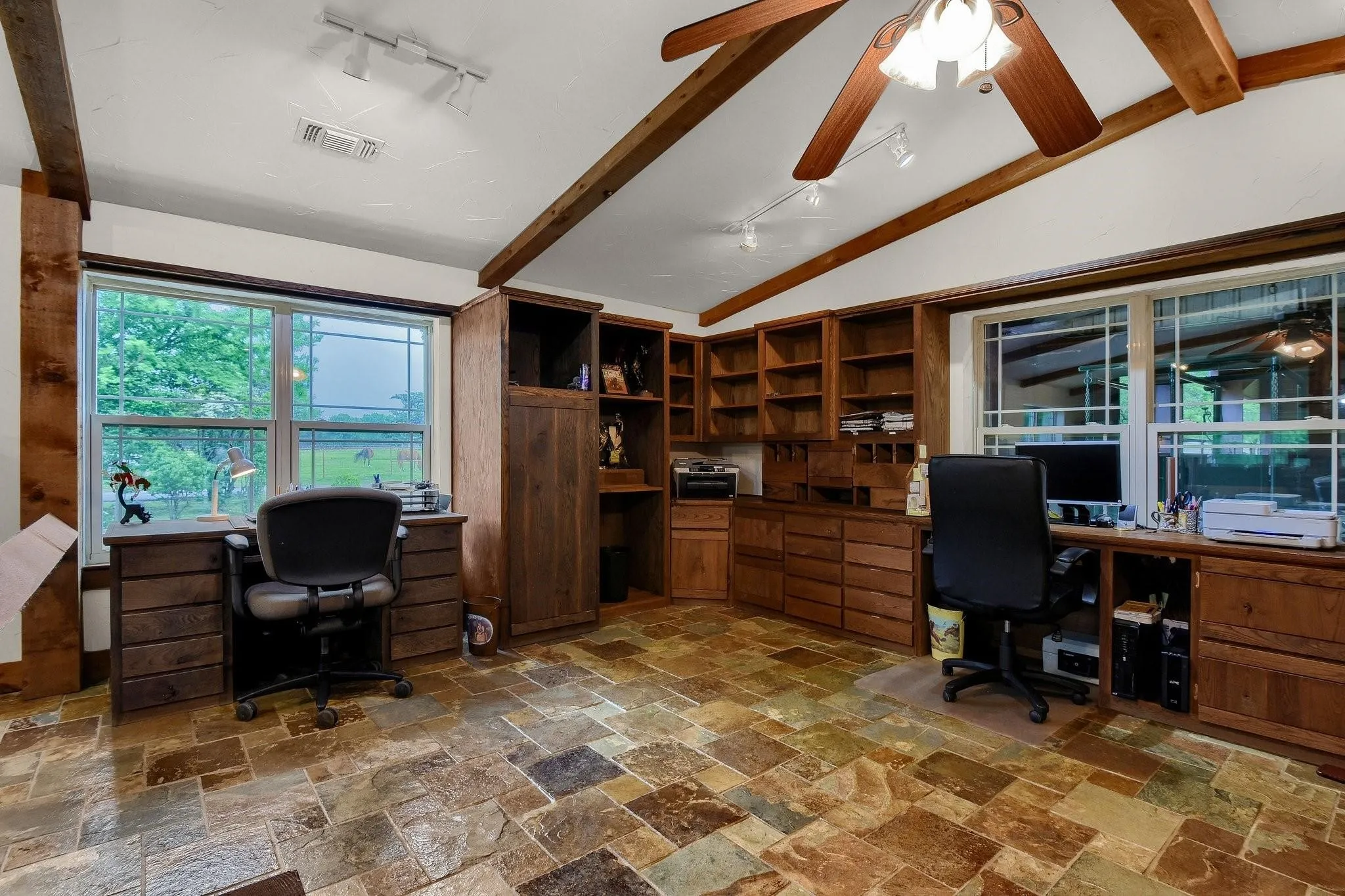 Office with track lighting, built in study area, light stone finish floors, and ceiling fan