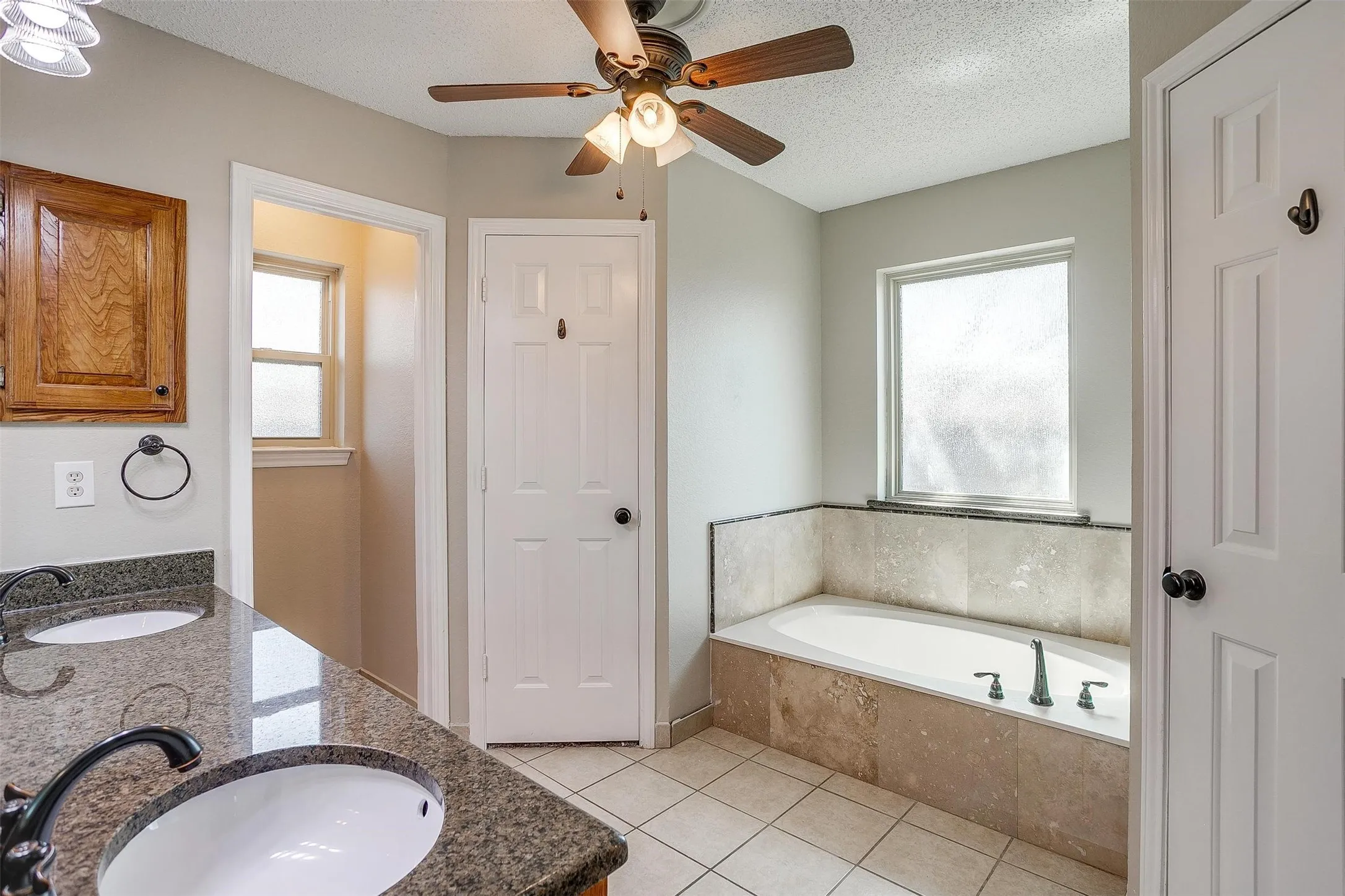 Dual vanity with granite-style countertop, undermount sinks, and dark-toned fixtures