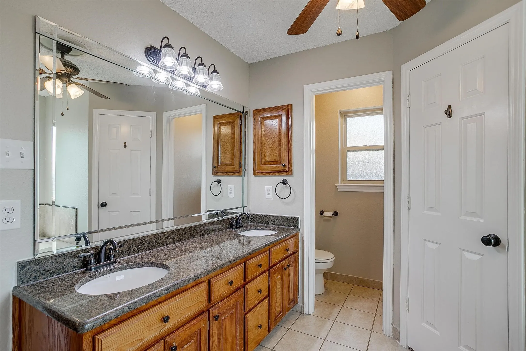 Dual vanity with undermount sinks, stone countertop, and wood cabinetry