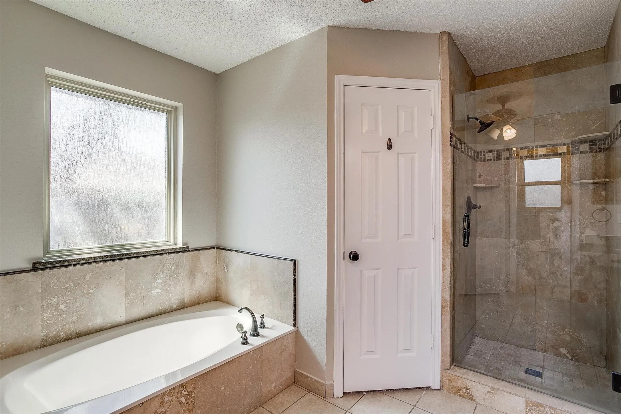 Deep soaking tub with stone tile surround and mosaic accent
