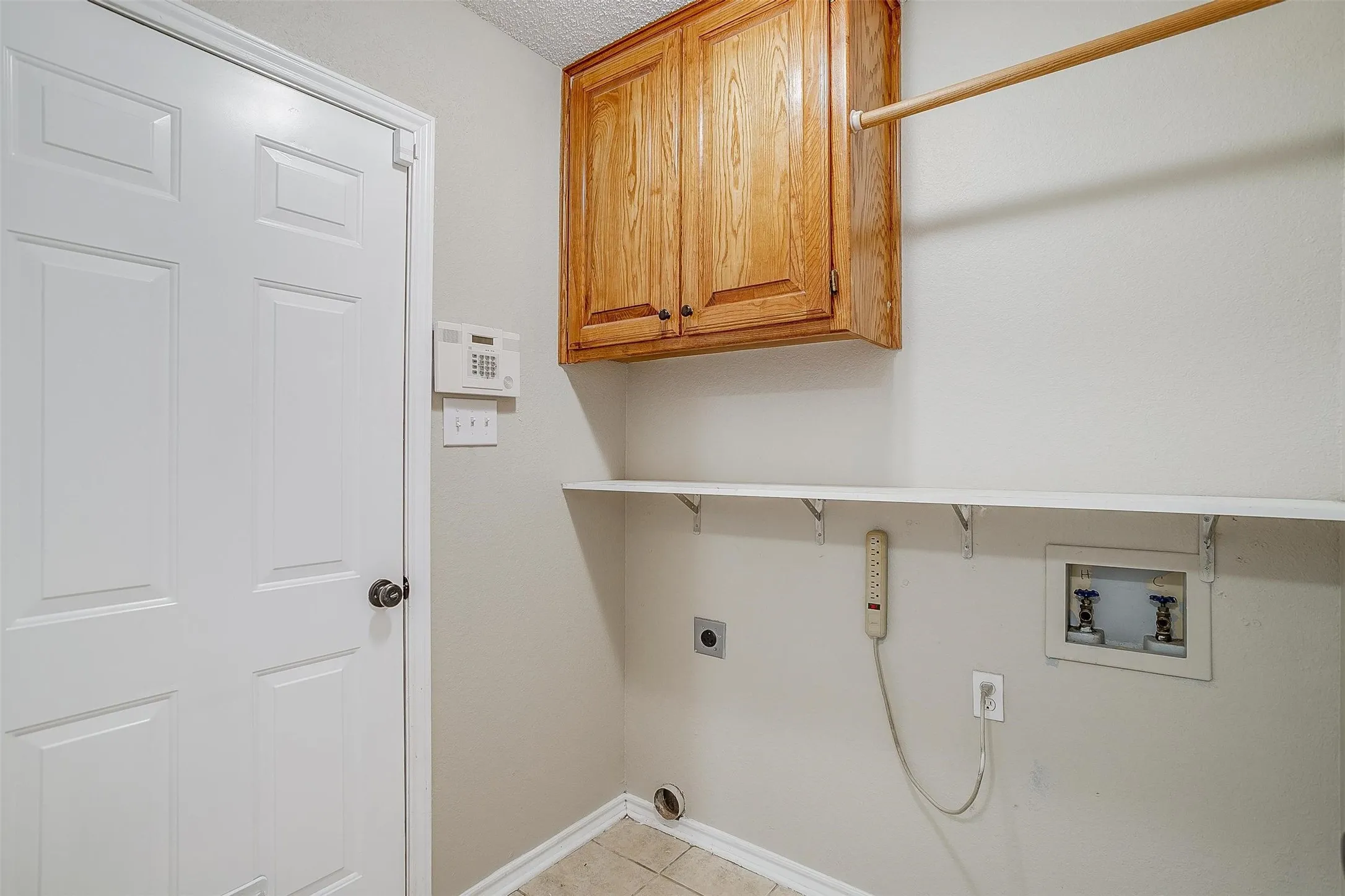 Tile flooring, wood-finish cabinetry, white built-in shelving, and a hanging rod