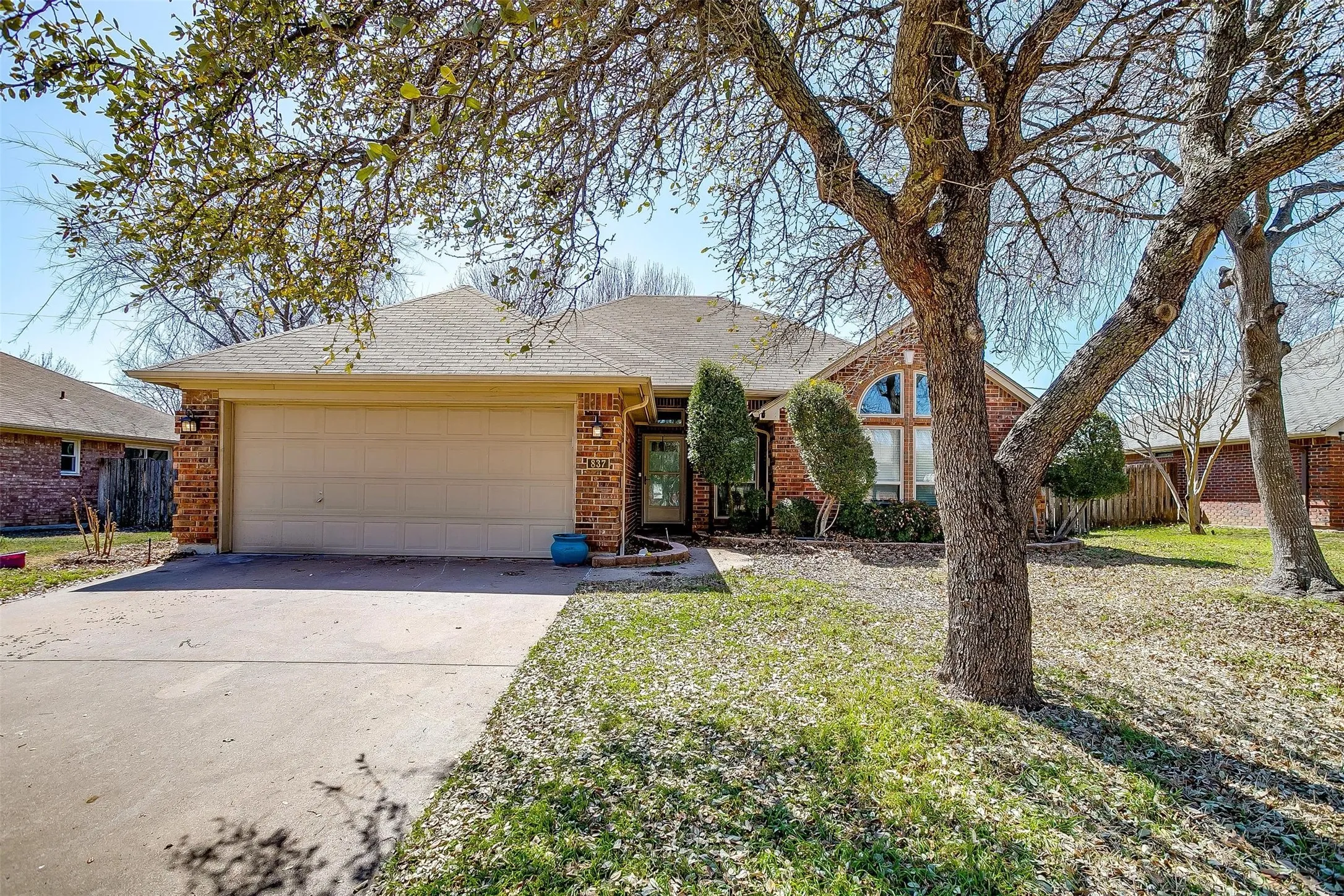 Brick exterior with an arched window, attached garage, and concrete driveway