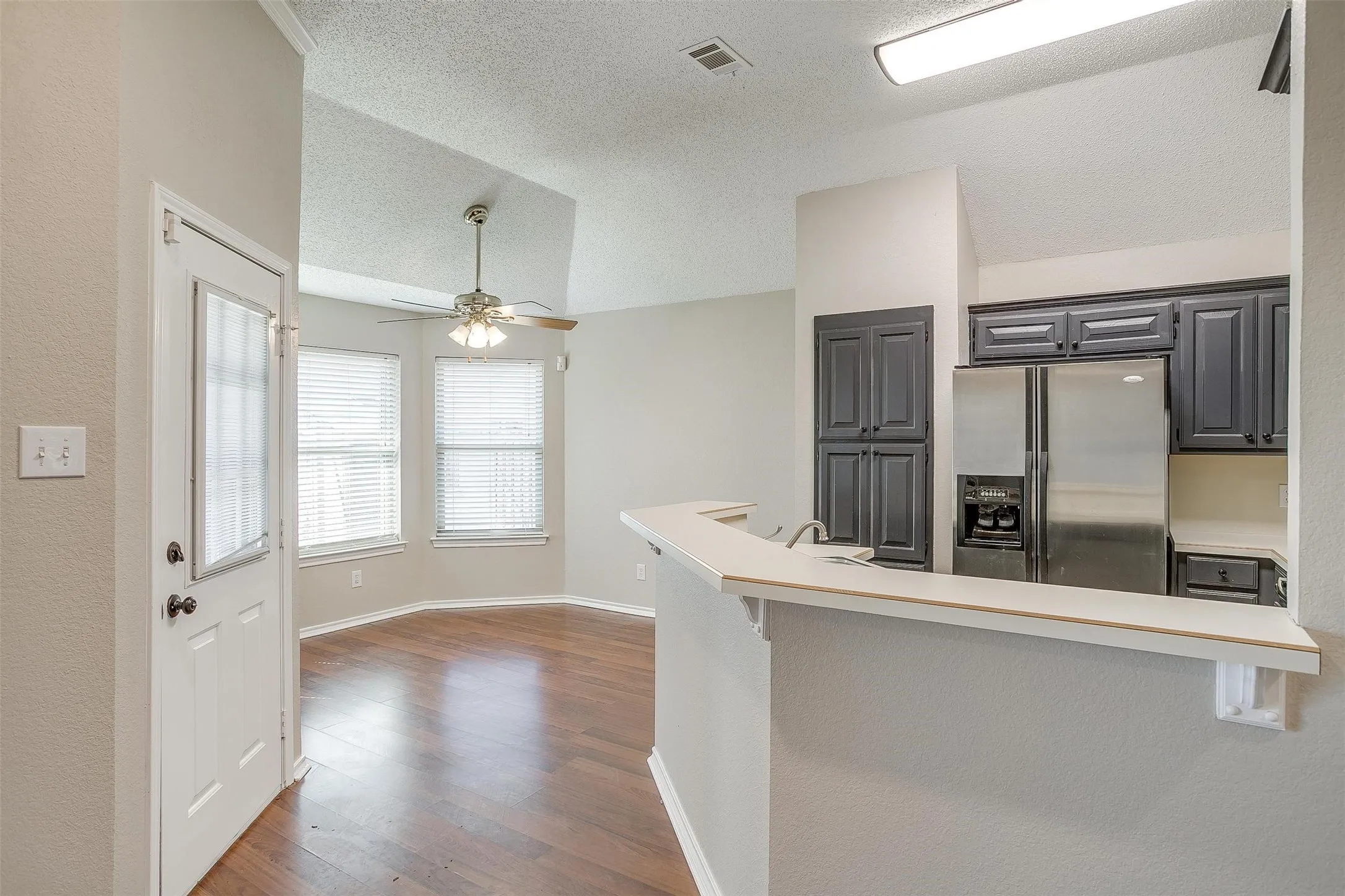 Kitchen featuring dark wood cabinetry, stainless steel refrigerator, and breakfast bar