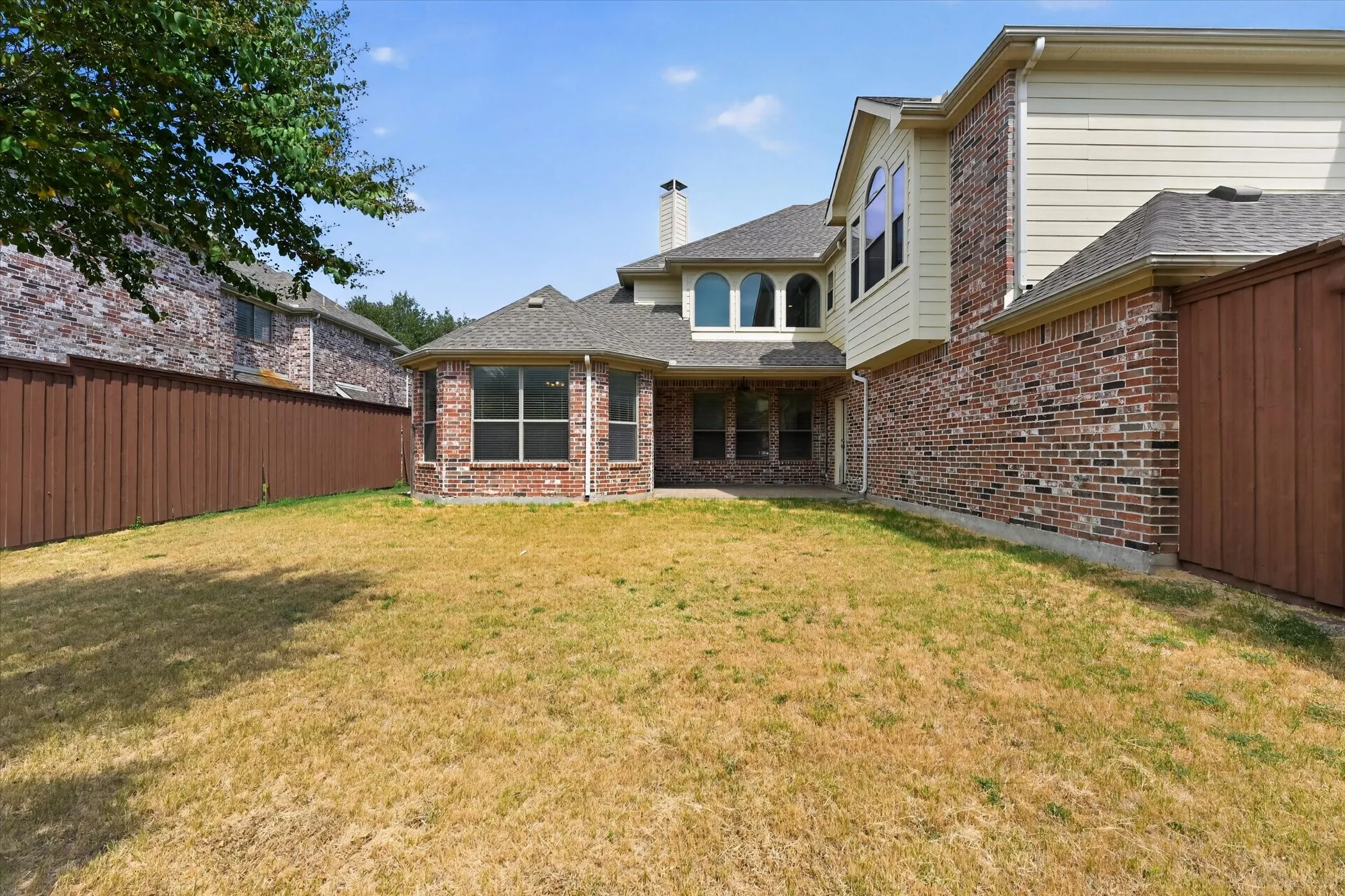 Brick and siding exterior featuring multiple windows and a private fenced yard