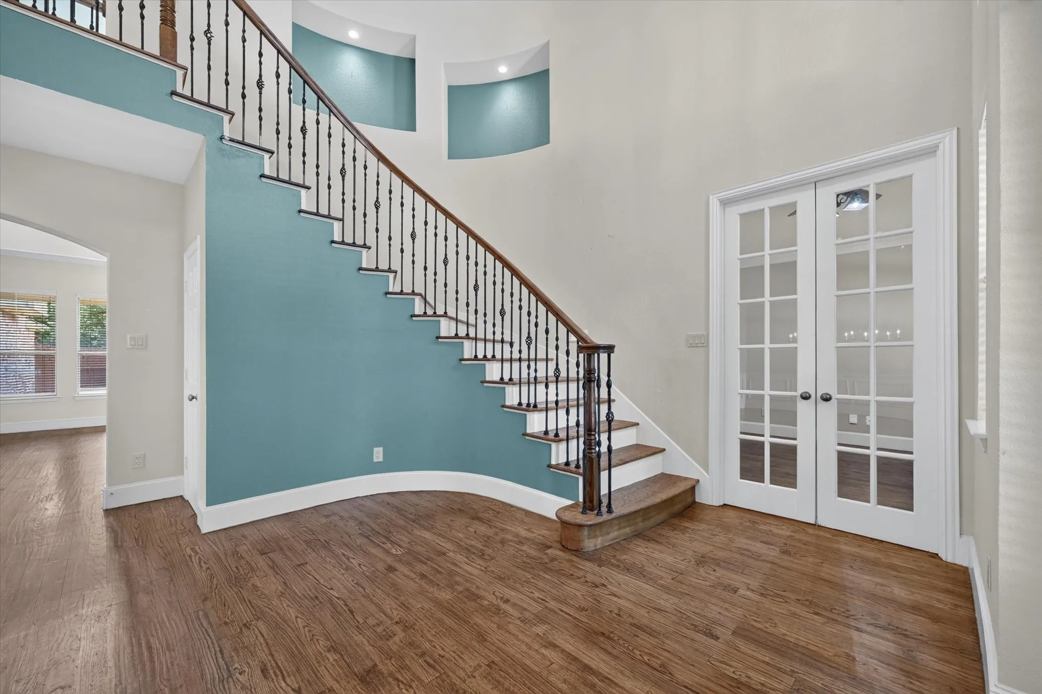 Grand staircase with wrought iron balusters and wood treads