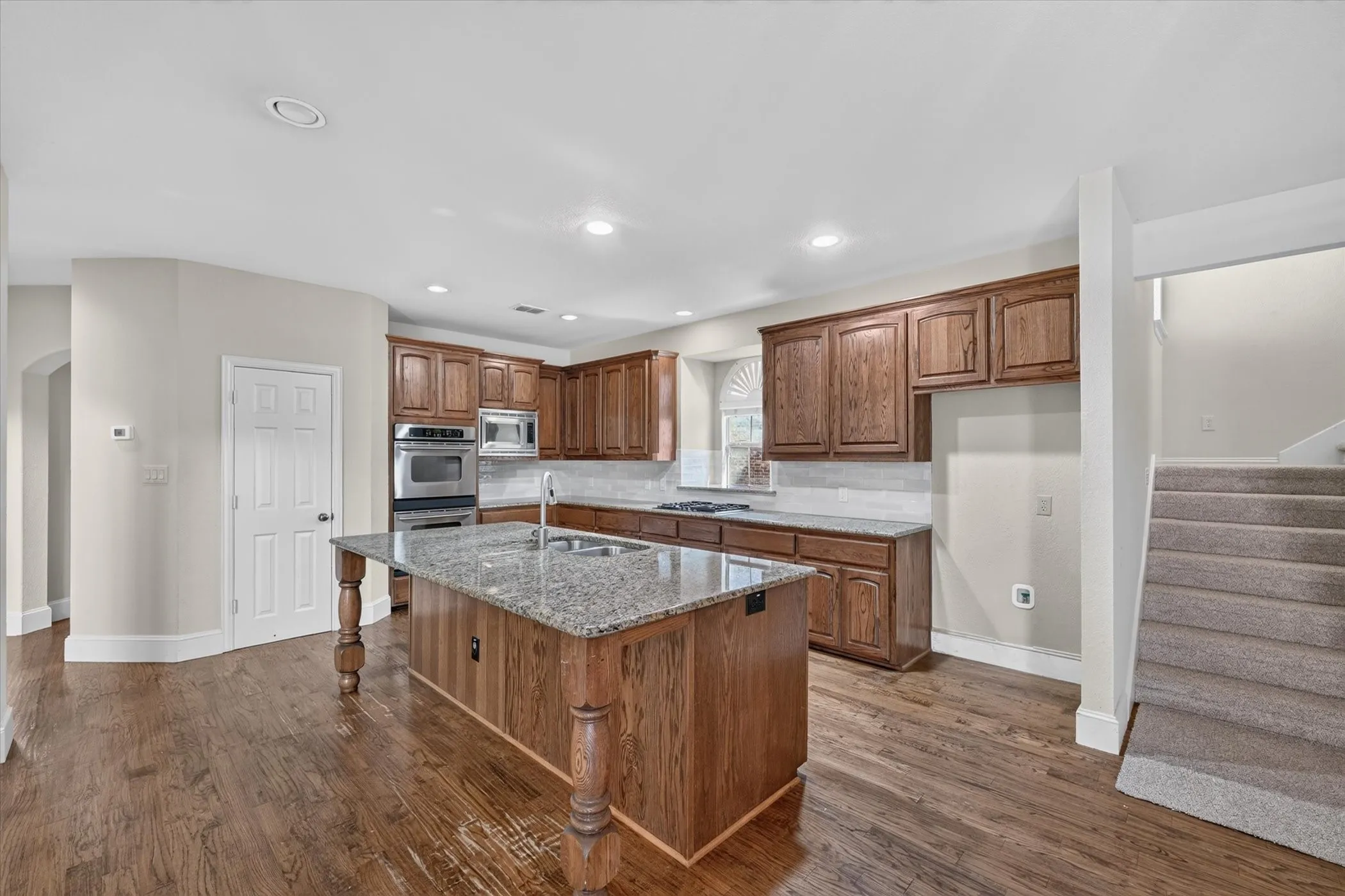 Kitchen featuring wood-finish flooring, recessed lighting, wood cabinetry, stone countertops, and stainless steel appliances