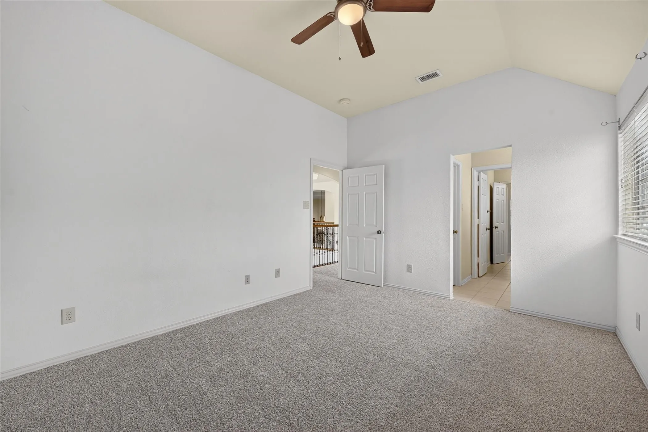 Vaulted ceilings with a ceiling fan, neutral carpet flooring, and window blinds
