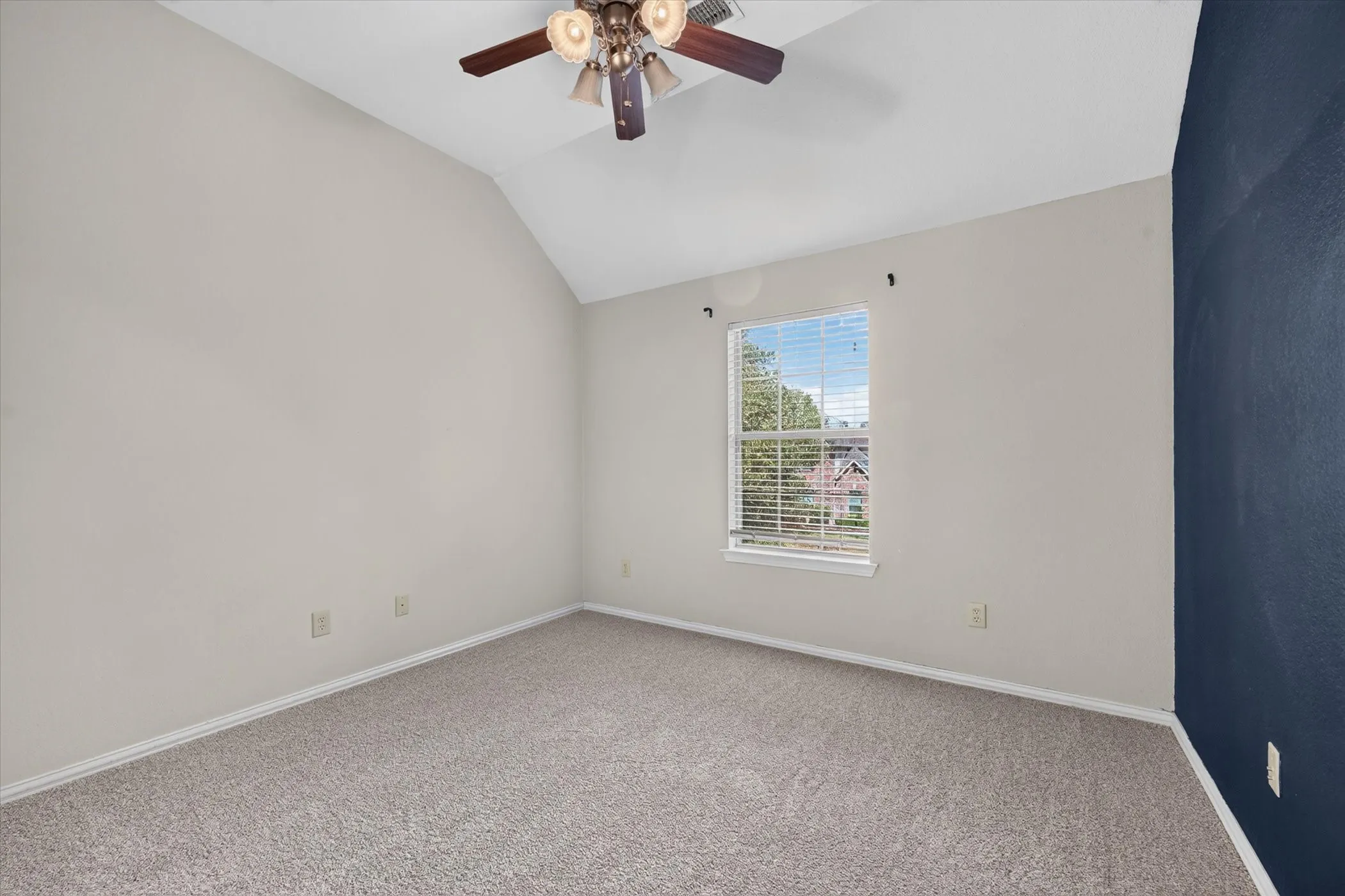 Vaulted ceiling with a ceiling fan, carpet flooring, and a single window with blinds