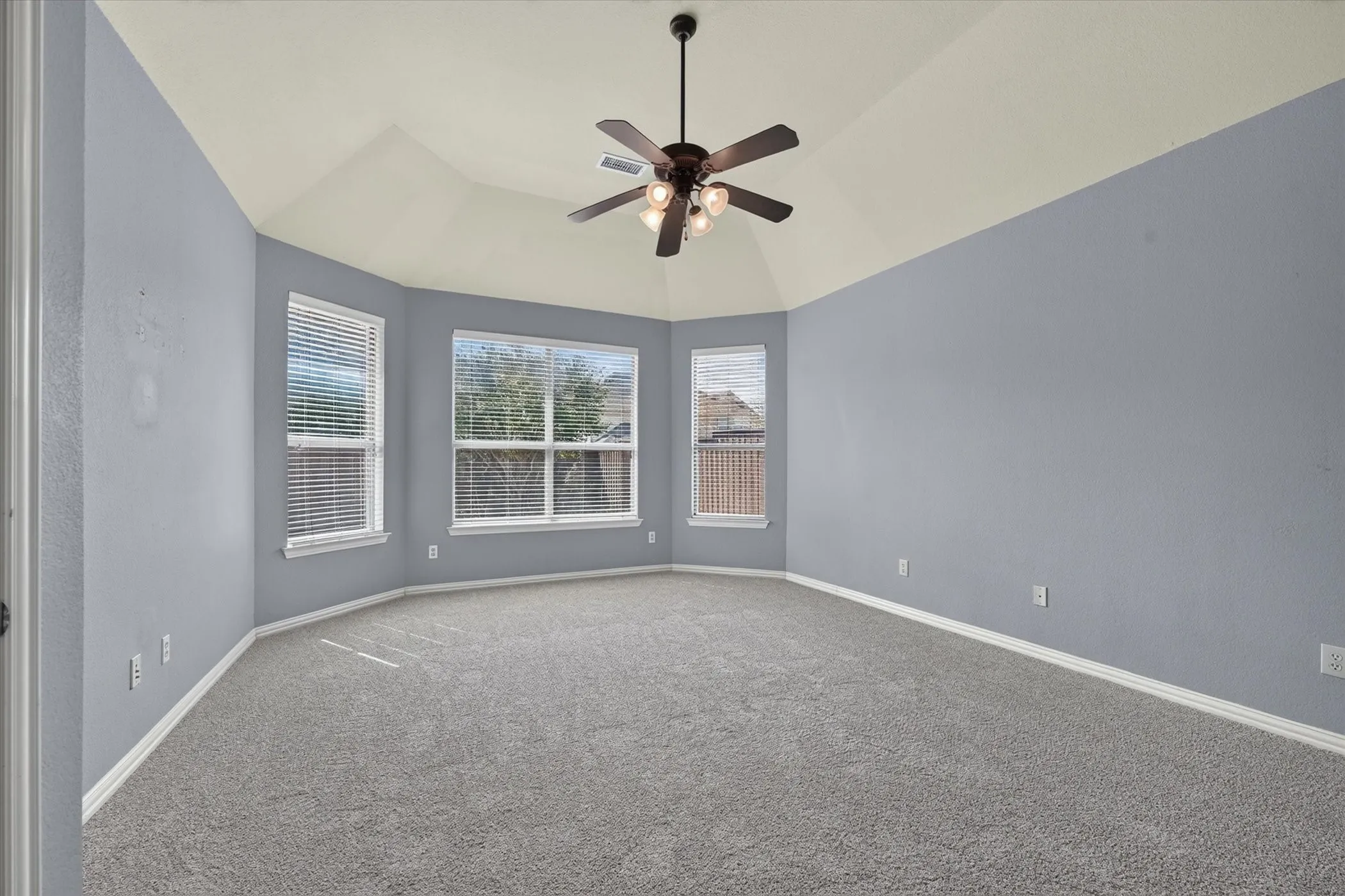 Vaulted ceiling, ceiling fan, carpeting, multiple windows with blinds, and white trim