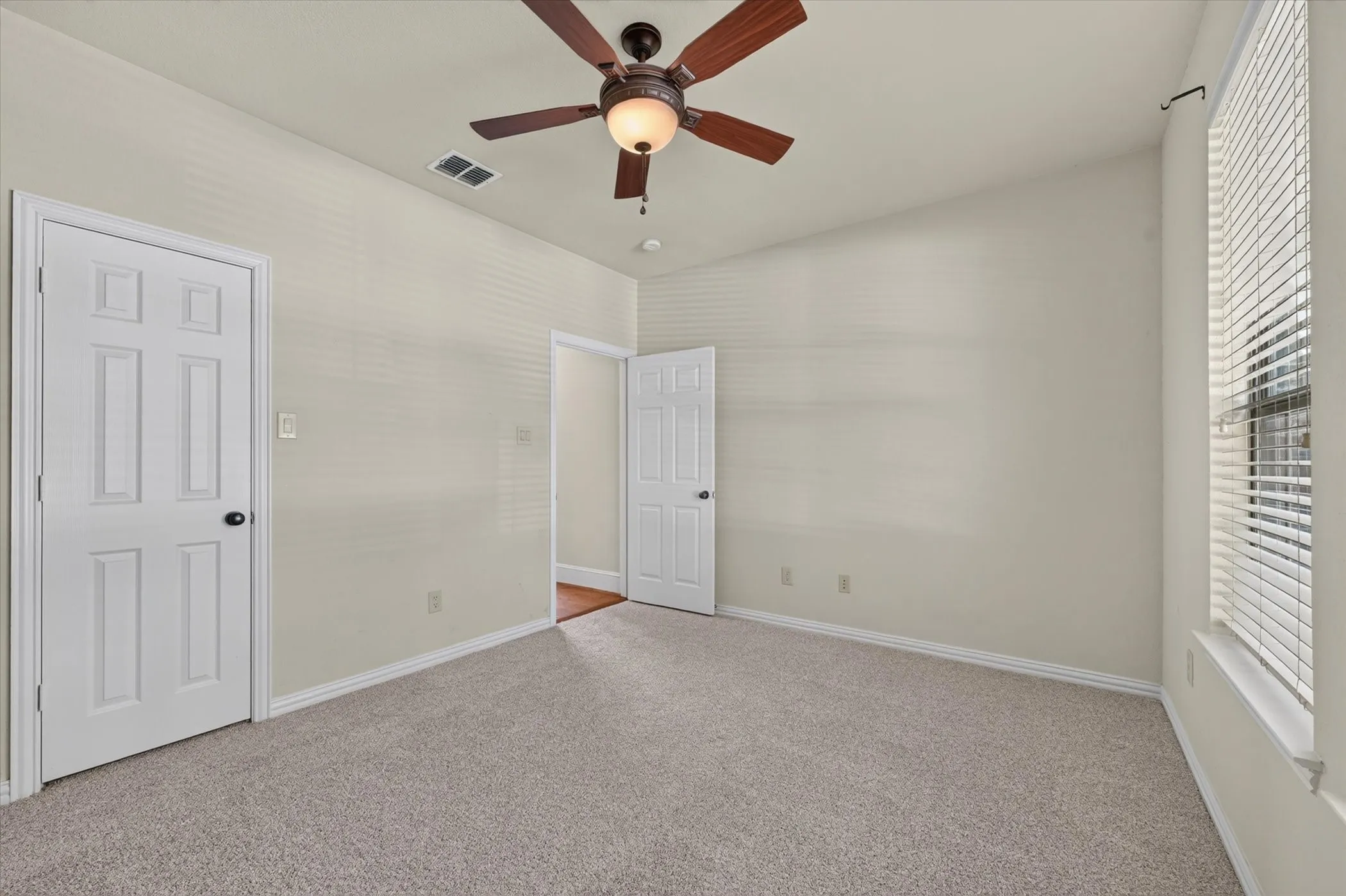Vaulted ceiling with a ceiling fan, light gray carpet, white trim, and a window with blinds