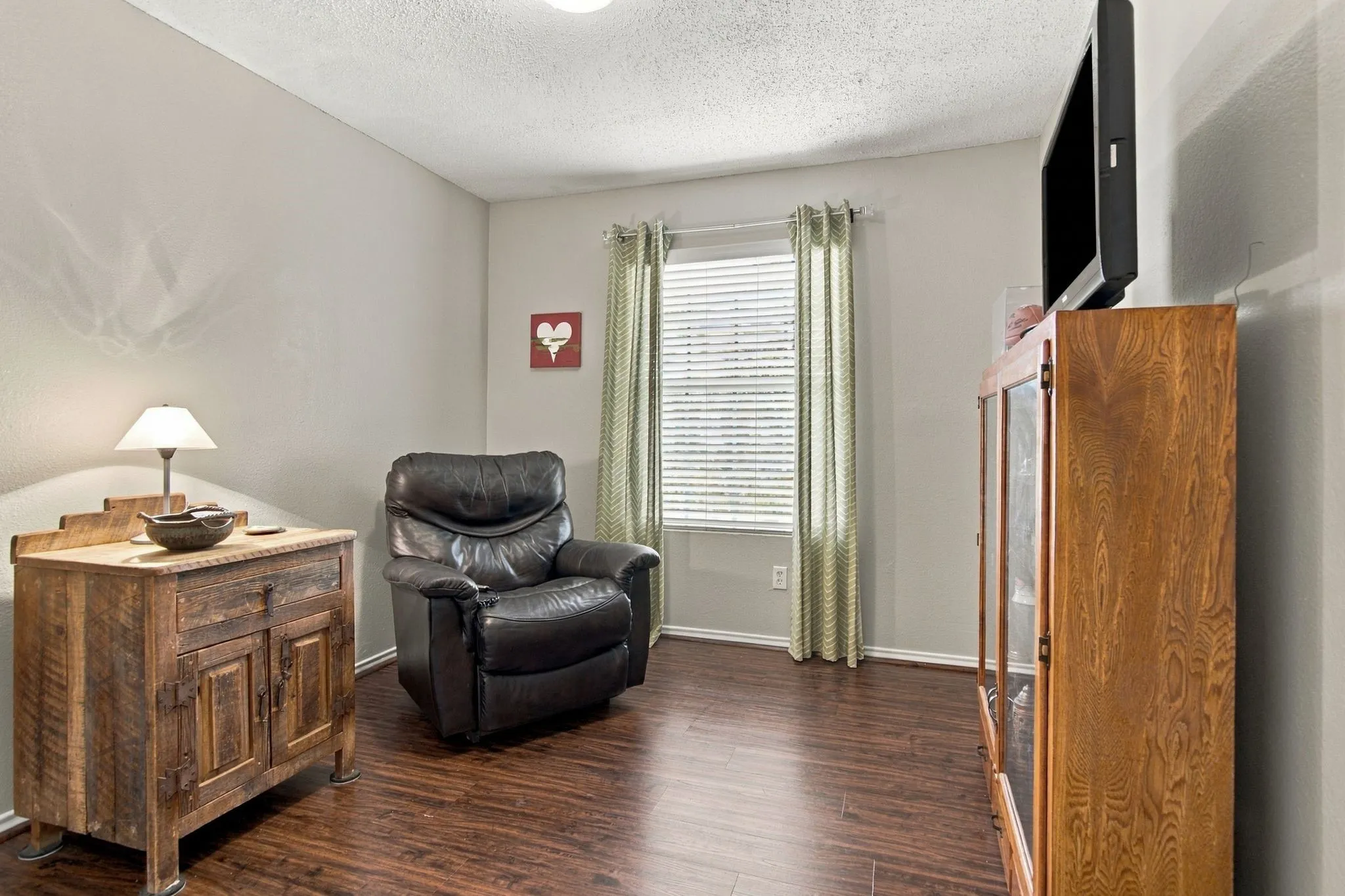 Wood-finish flooring with a neutral wall color and window blinds