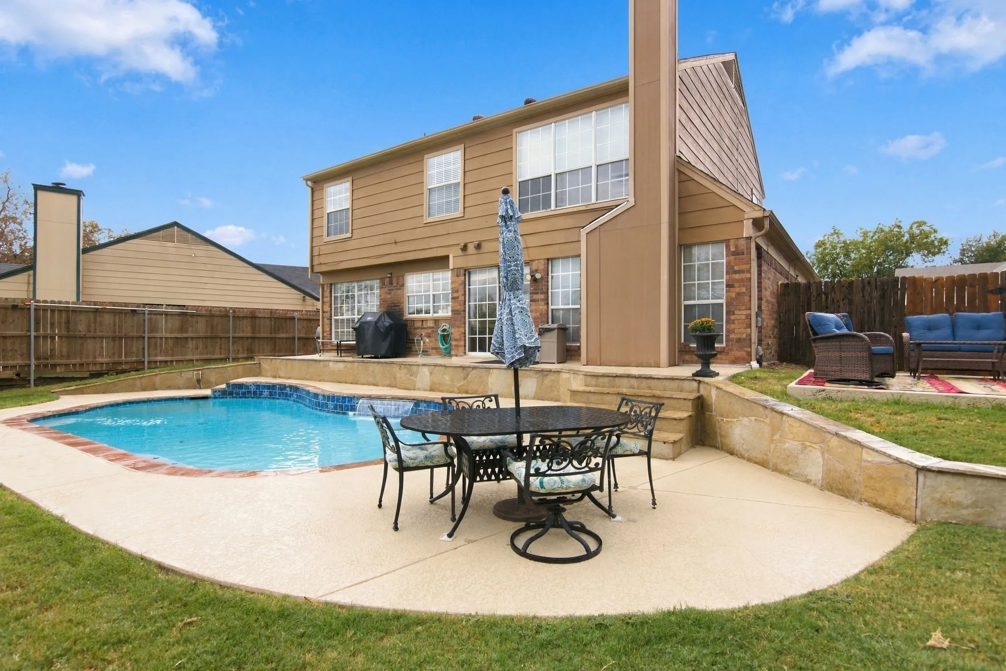 Rear exterior with a swimming pool, concrete patio, and retaining walls
