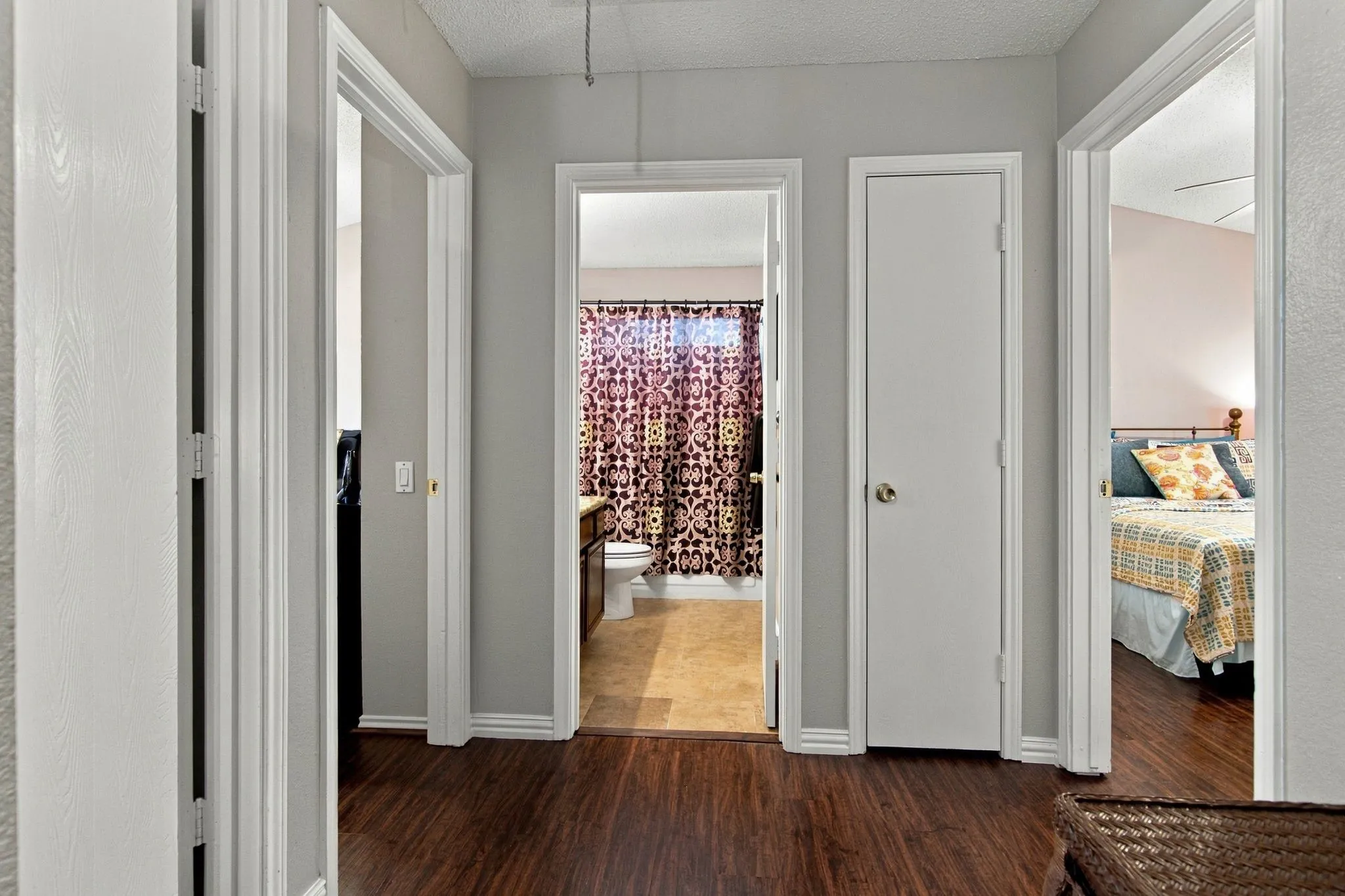 Hallway with wood-finish flooring, light gray wall paint, and white trim