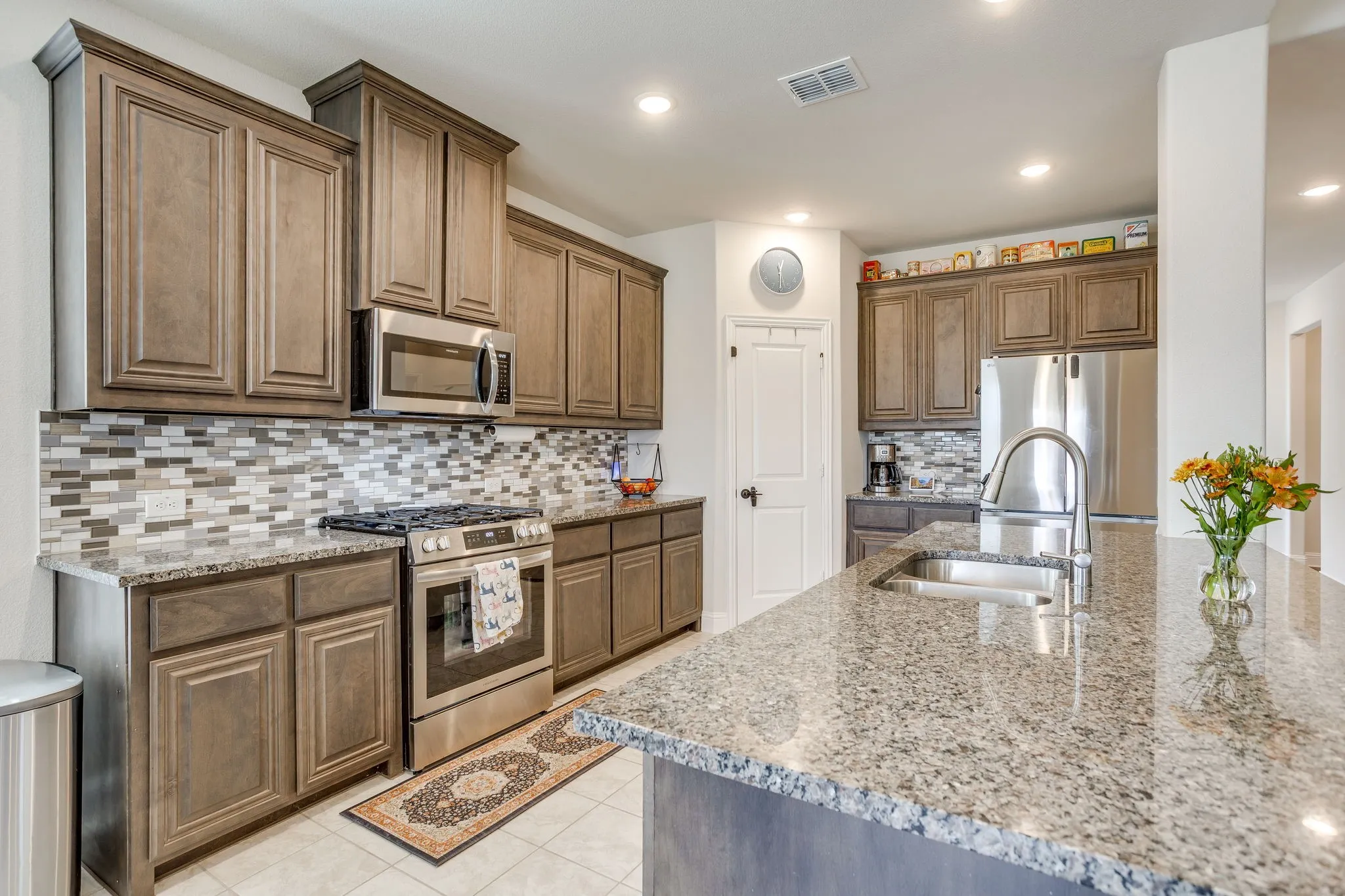 Kitchen featuring a large island with an undermount sink, ample cabinetry, stainless steel appliances, and tile backsplash