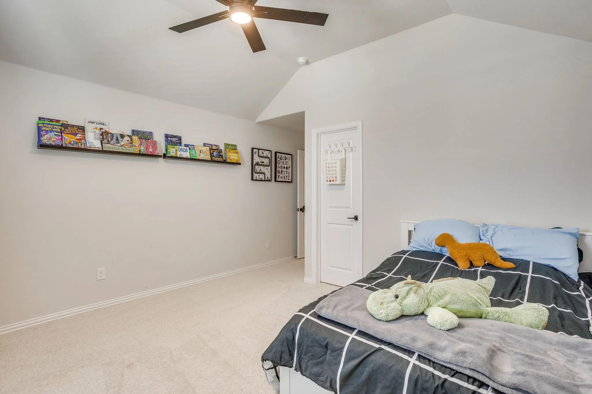 Vaulted ceiling with a ceiling fan, light-toned carpeting, and a built-in wall shelf