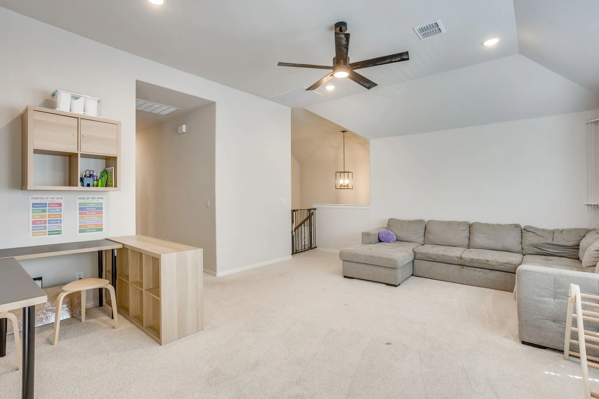 Vaulted ceiling, recessed lighting, ceiling fan, and staircase with wrought iron balusters