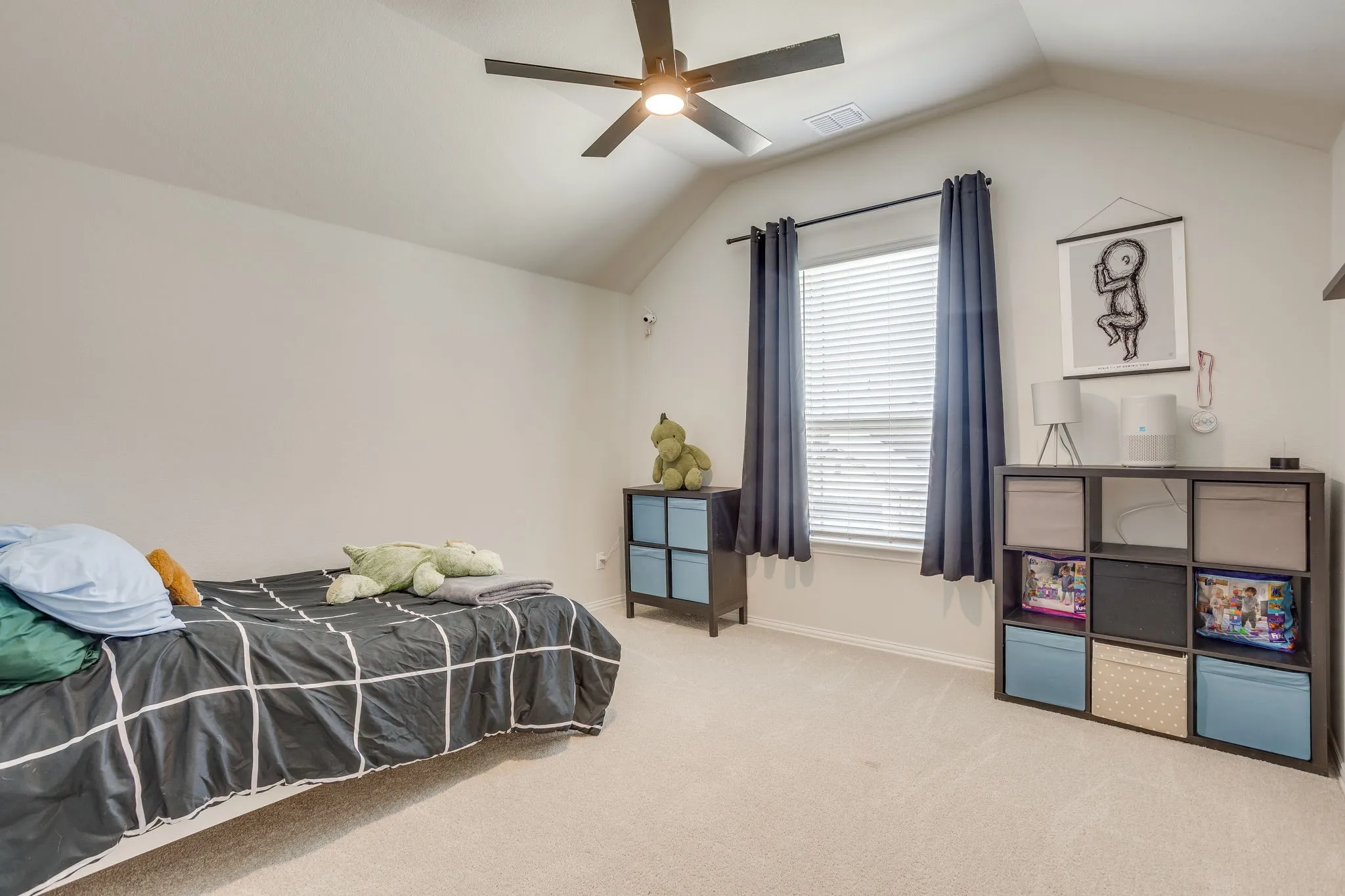 Angled ceiling, recessed window, ceiling fan with light, and light-colored carpeting