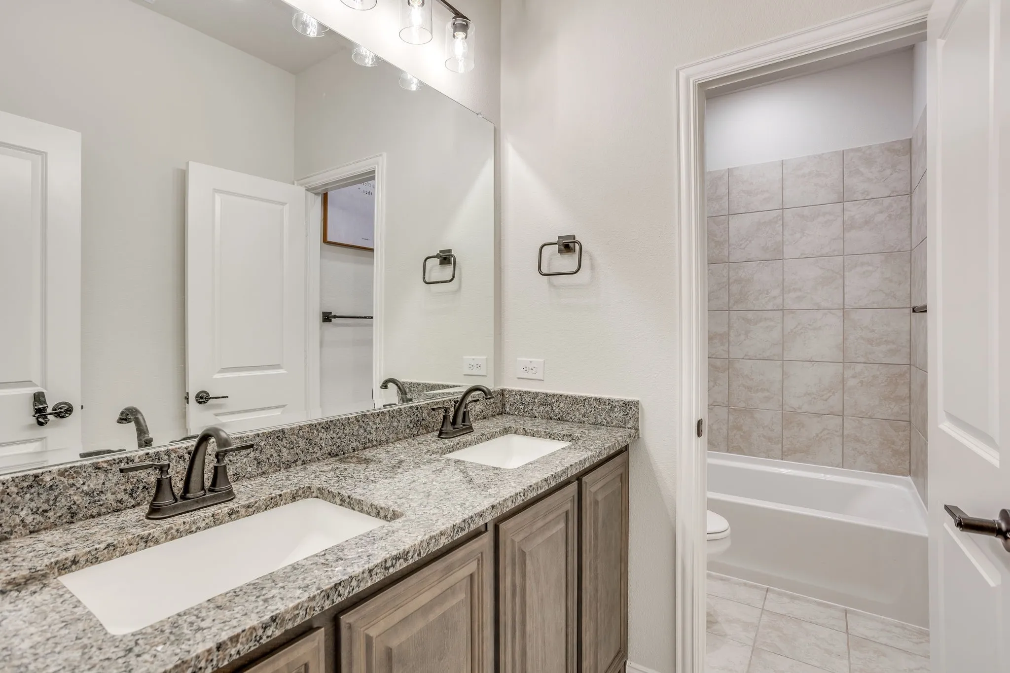 Dual vanity with granite countertops, undermount sinks, and bronze-finish fixtures