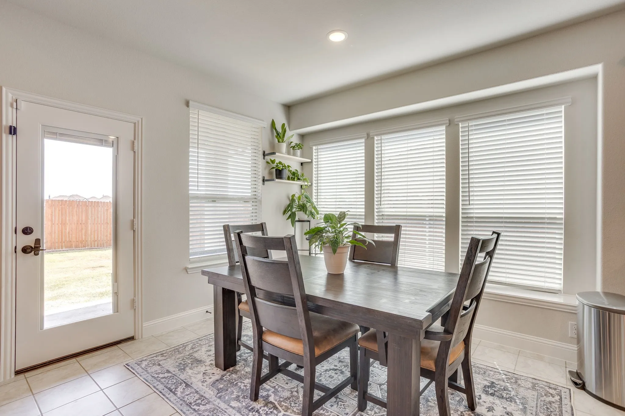 Recessed ceiling lighting, tiled flooring, built-in shelving, white window blinds, and a glass-paneled door