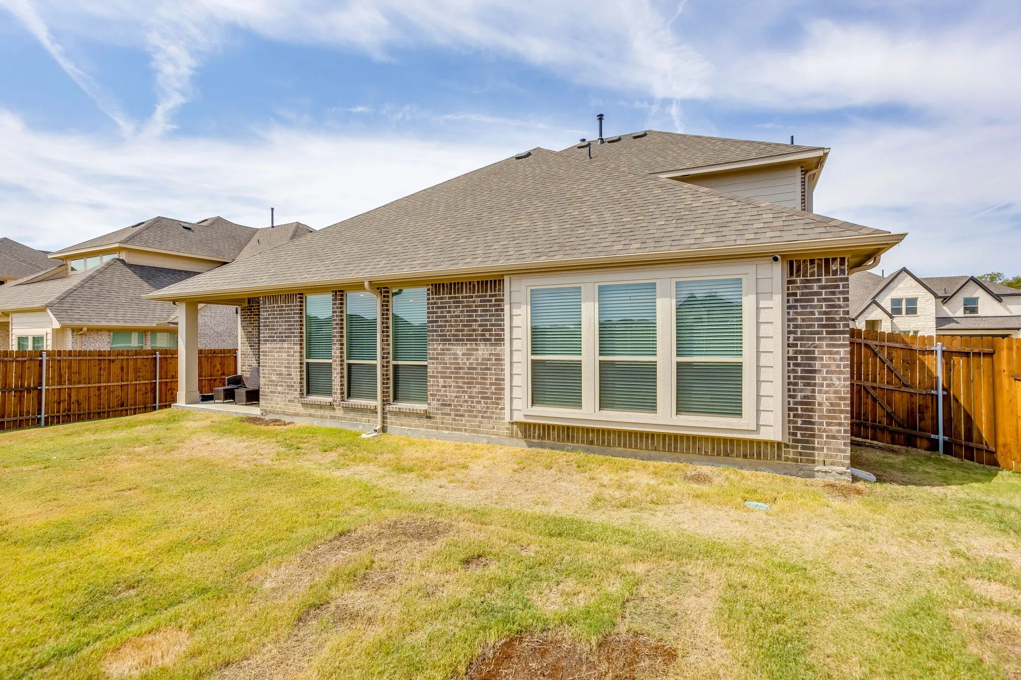 Brick exterior with an expansive backyard and a covered patio area