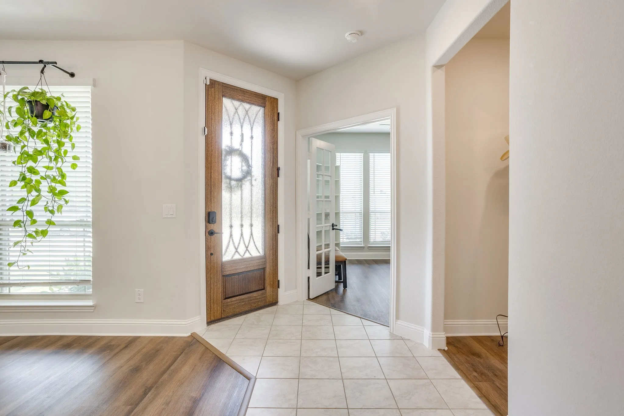 Entryway featuring a decorative glass front door, tile flooring, and wood-finish flooring