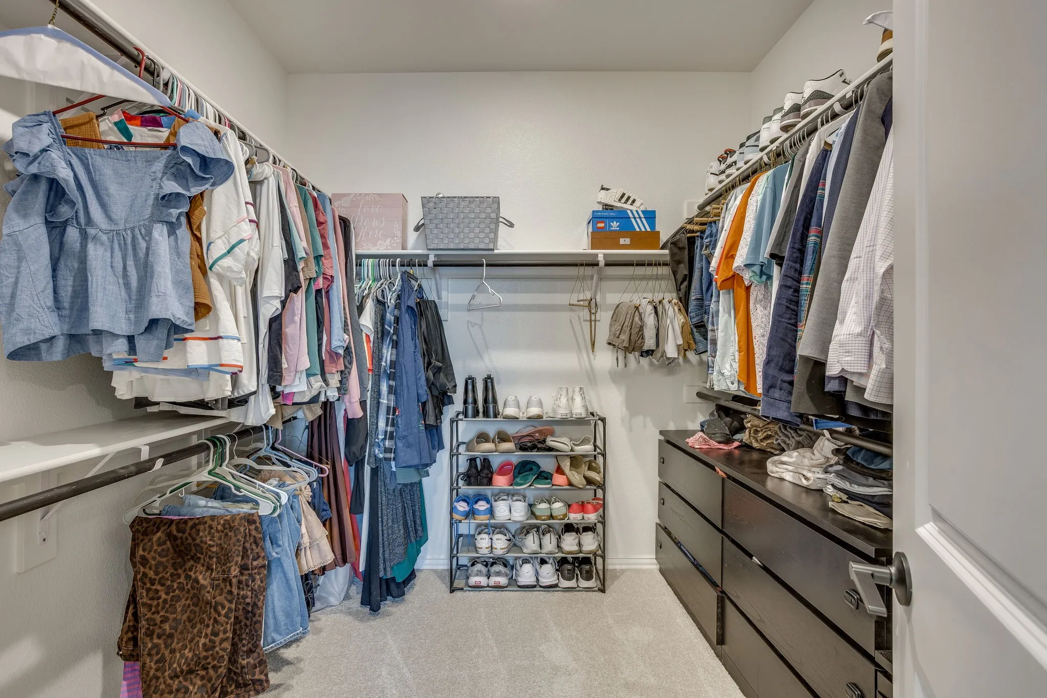 Built-in closet system with shelving, hanging rods, and dark wood-finish drawers