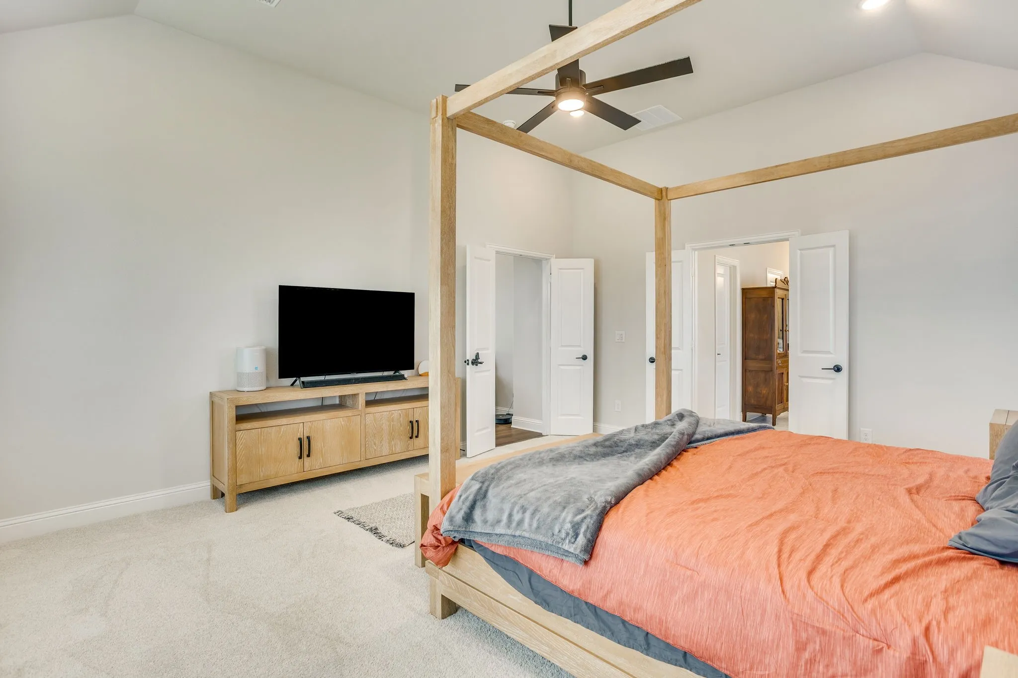 Vaulted ceiling with a ceiling fan, light-toned carpeting, and white paneled doors