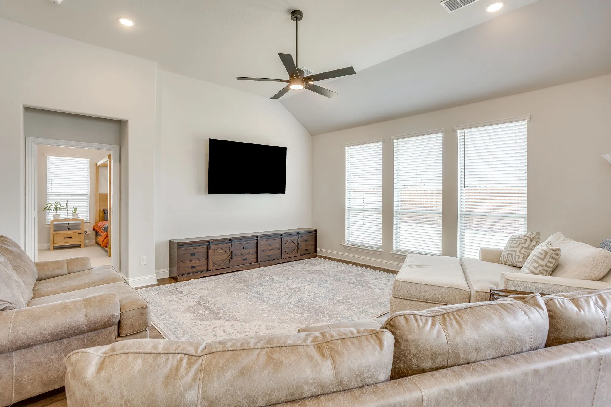 Vaulted ceiling with a ceiling fan, recessed lighting, and wood-finish flooring