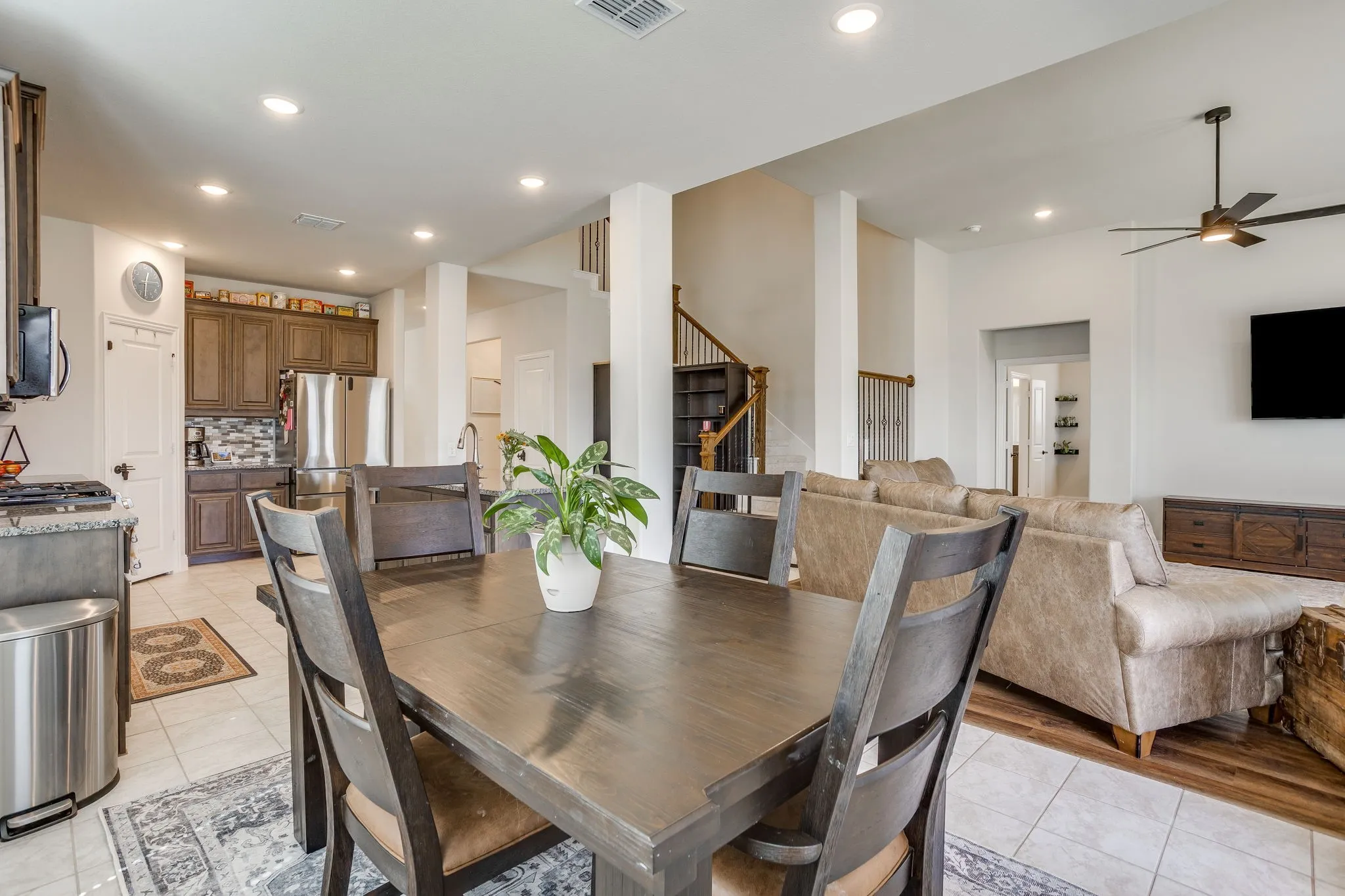 Open concept living space featuring recessed lighting, a kitchen with dark wood-finish cabinetry, stainless steel appliances, and a staircase with wood-finish treads