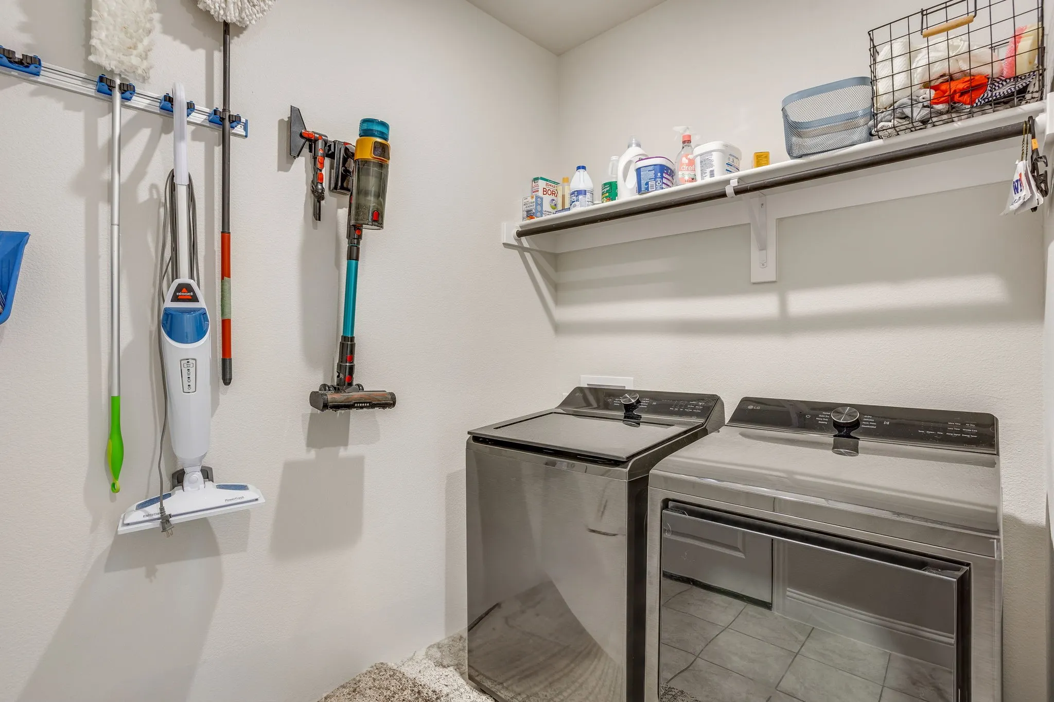 Dedicated laundry area featuring a wall-mounted shelving unit, permanent wall organization system, and space for appliances