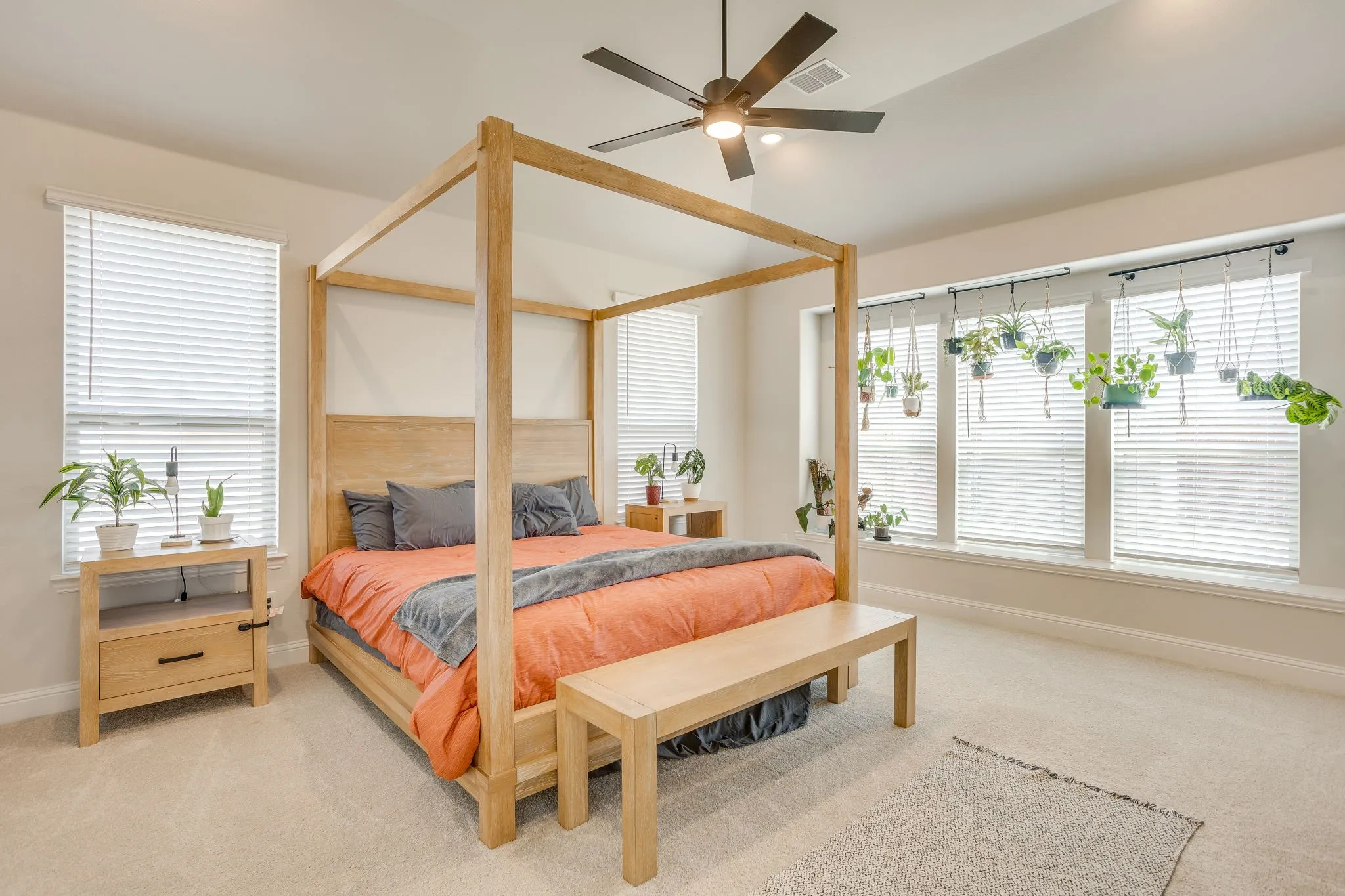 Neutral carpet flooring, ceiling fan with integrated lighting, multiple windows with blinds, and light-toned wall paint