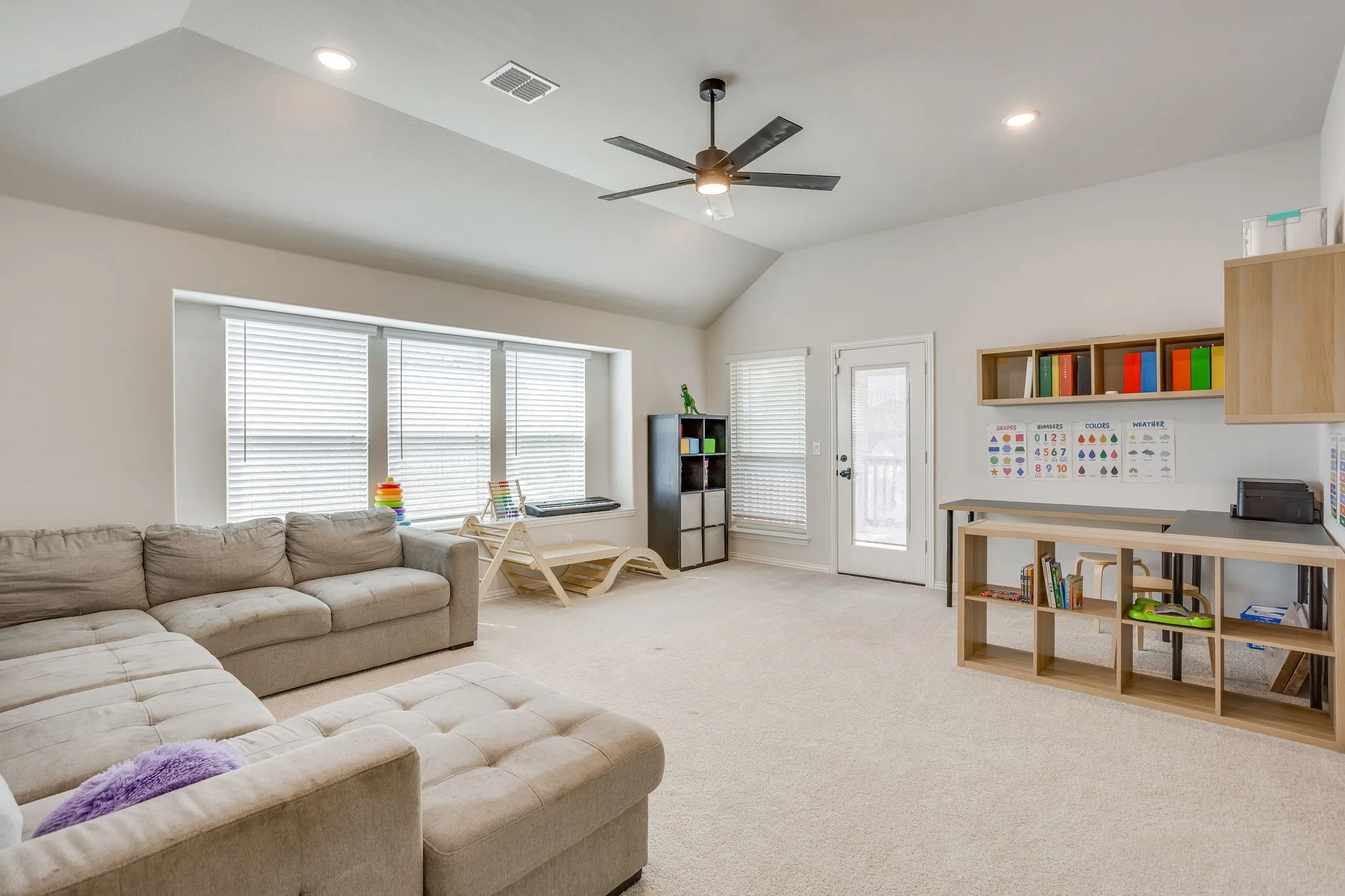 Vaulted ceiling, recessed lighting, ceiling fan, built-in shelving, and light wood-finish cabinetry