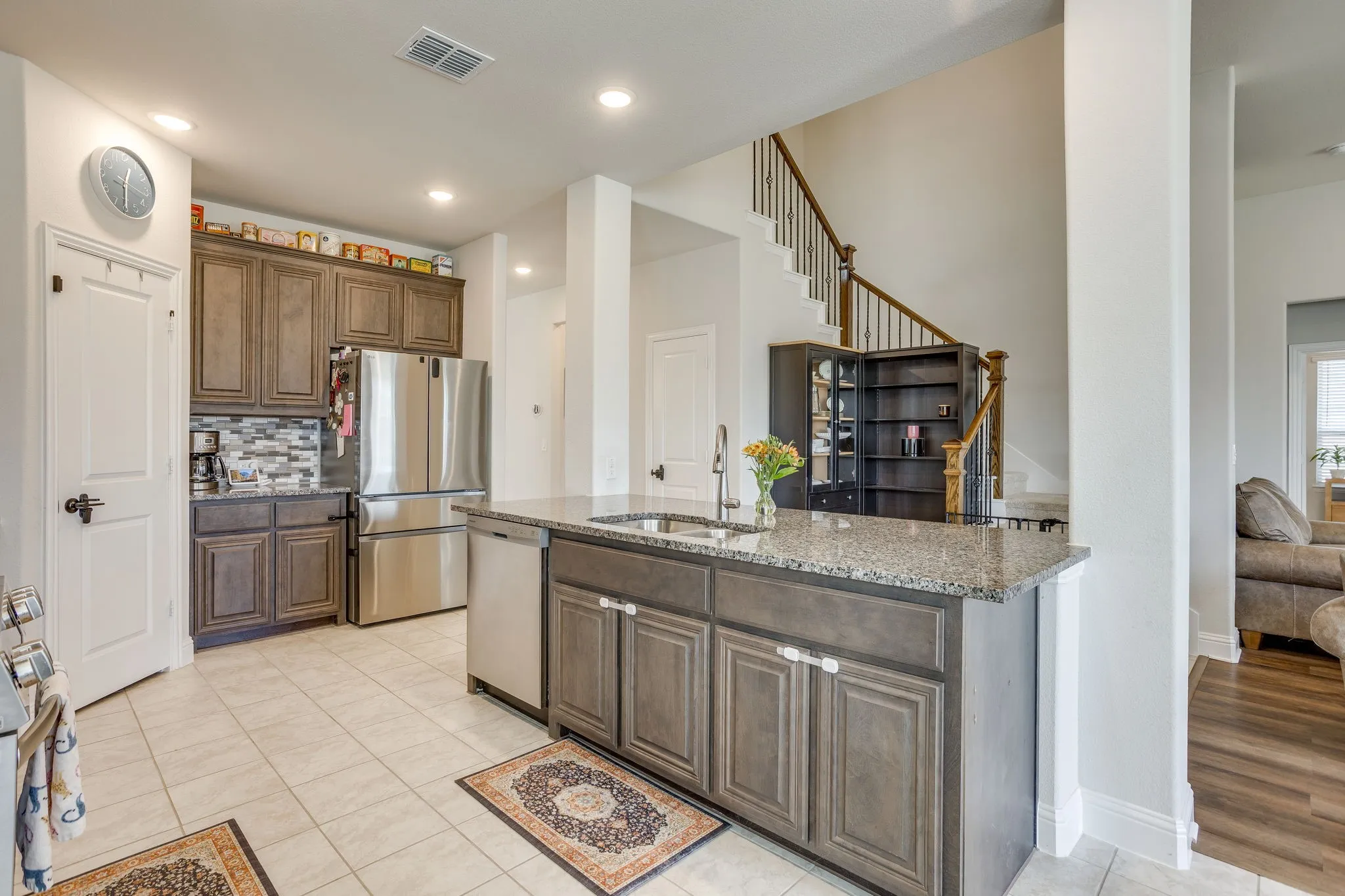 Kitchen featuring an island with sink, stainless steel appliances, tiled backsplash, and wood cabinetry