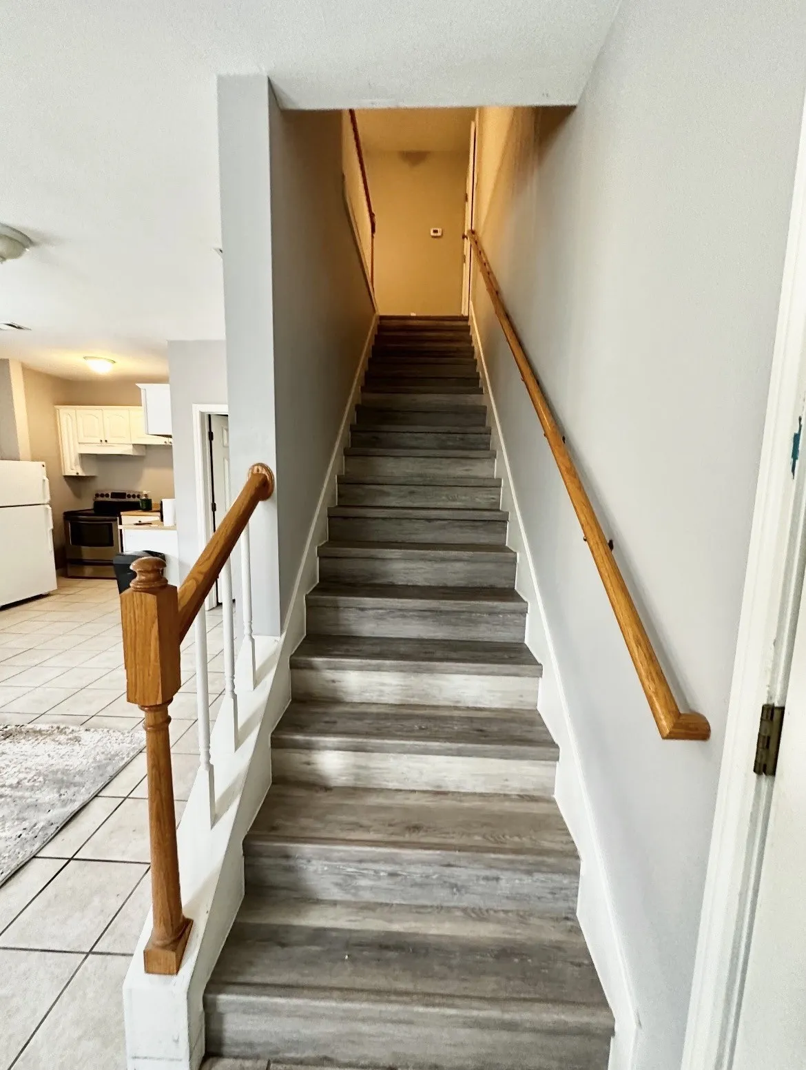 Staircase featuring wood-finish treads and risers, wood newel post, and wood handrails
