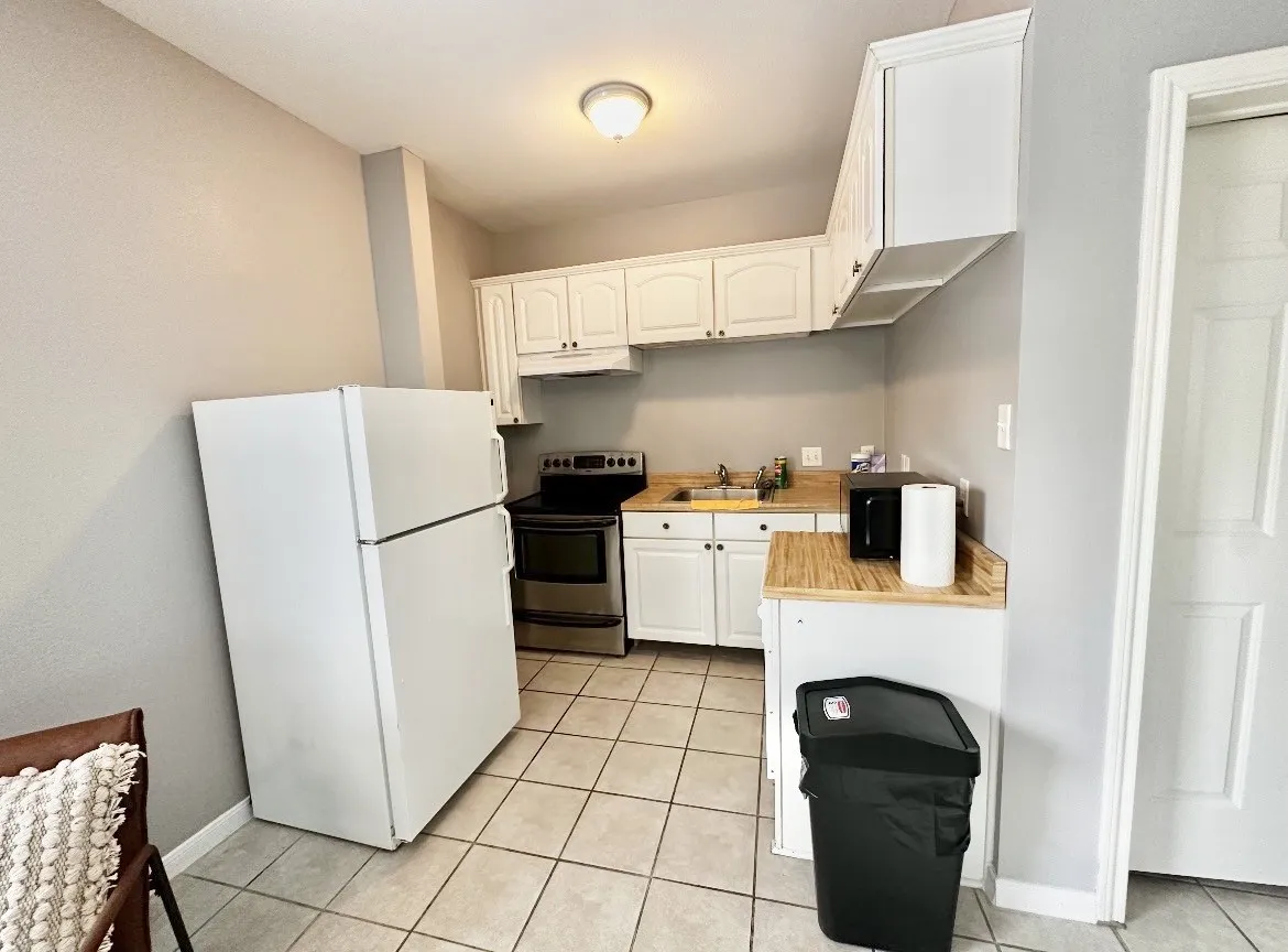 Kitchen featuring white upper and lower cabinetry, wood-finish countertops, and a white refrigerator