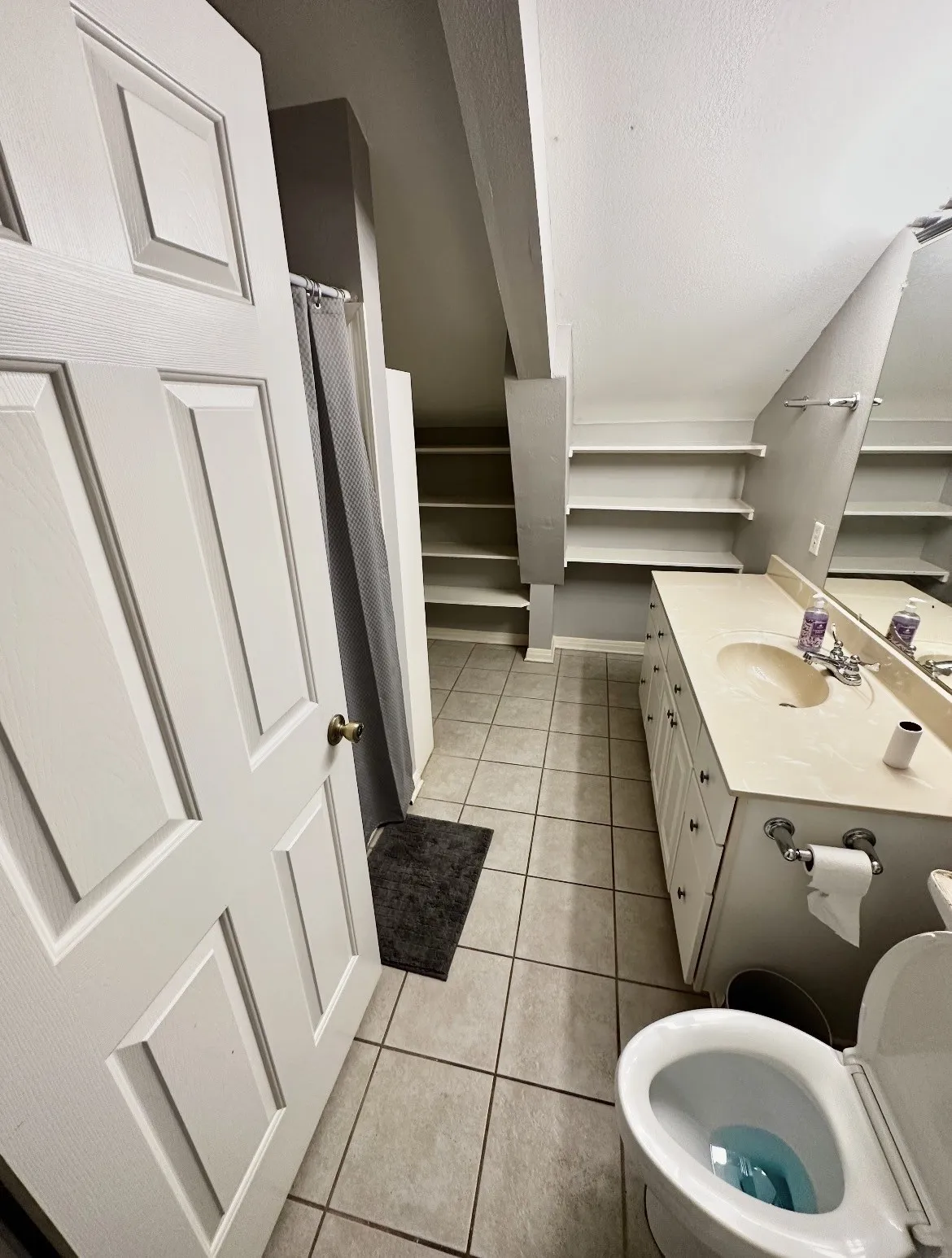 Bathroom featuring a double vanity, built-in shelving, tiled flooring, and a paneled door