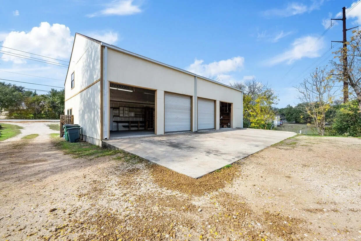 Metal-sided outbuilding featuring multiple bay doors and a concrete pad
